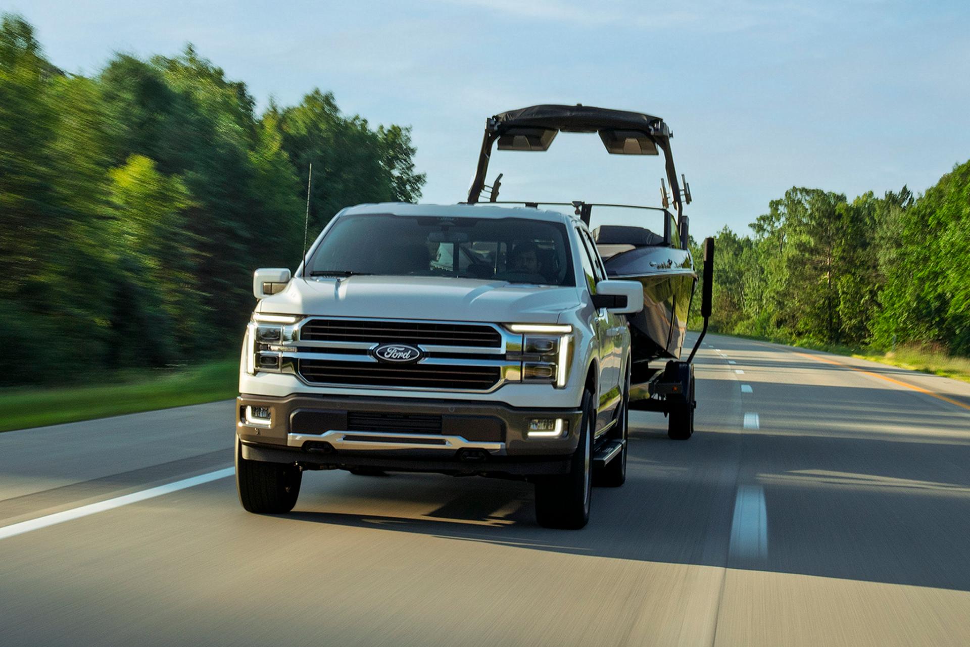 2027 Ford F-150 Lariat towing a boat on the highway