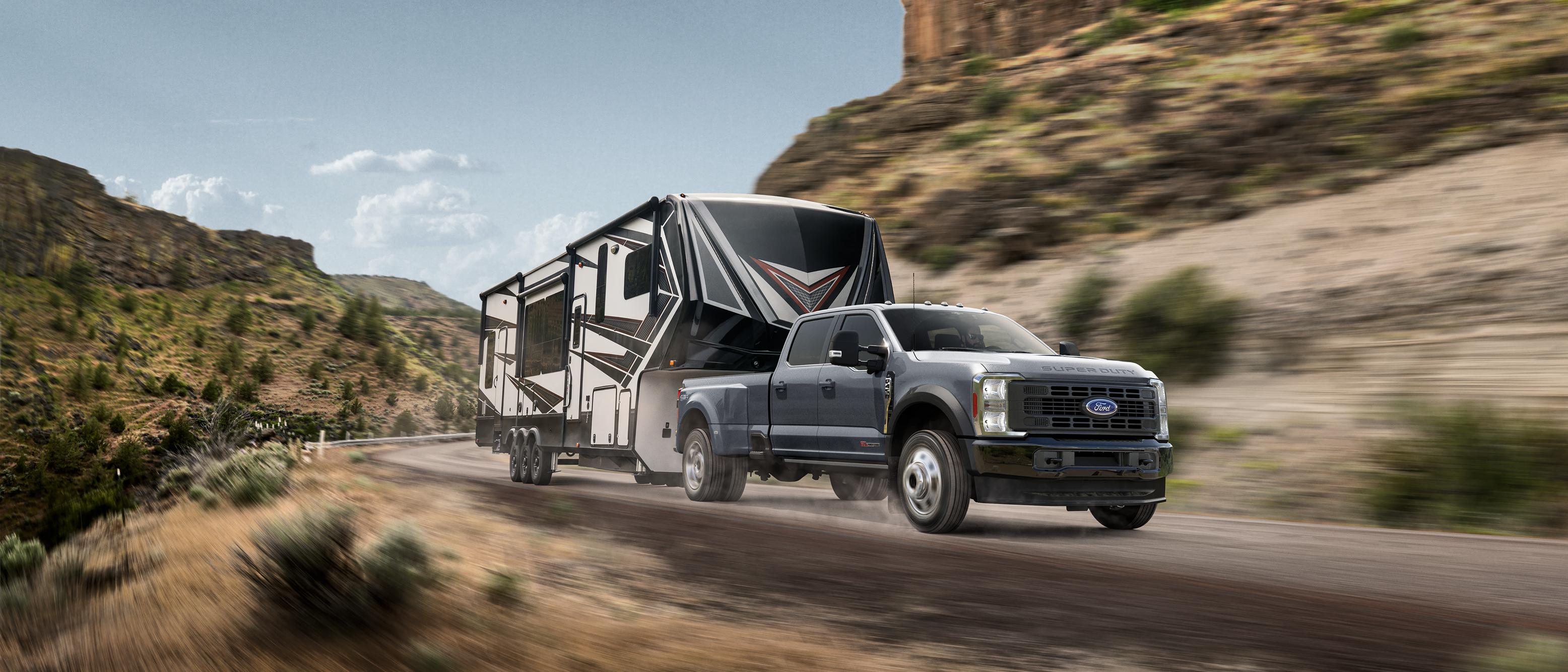 2025 Ford Super Duty® F-450® XL in Carbonized Gray pulling a camper down a winding road