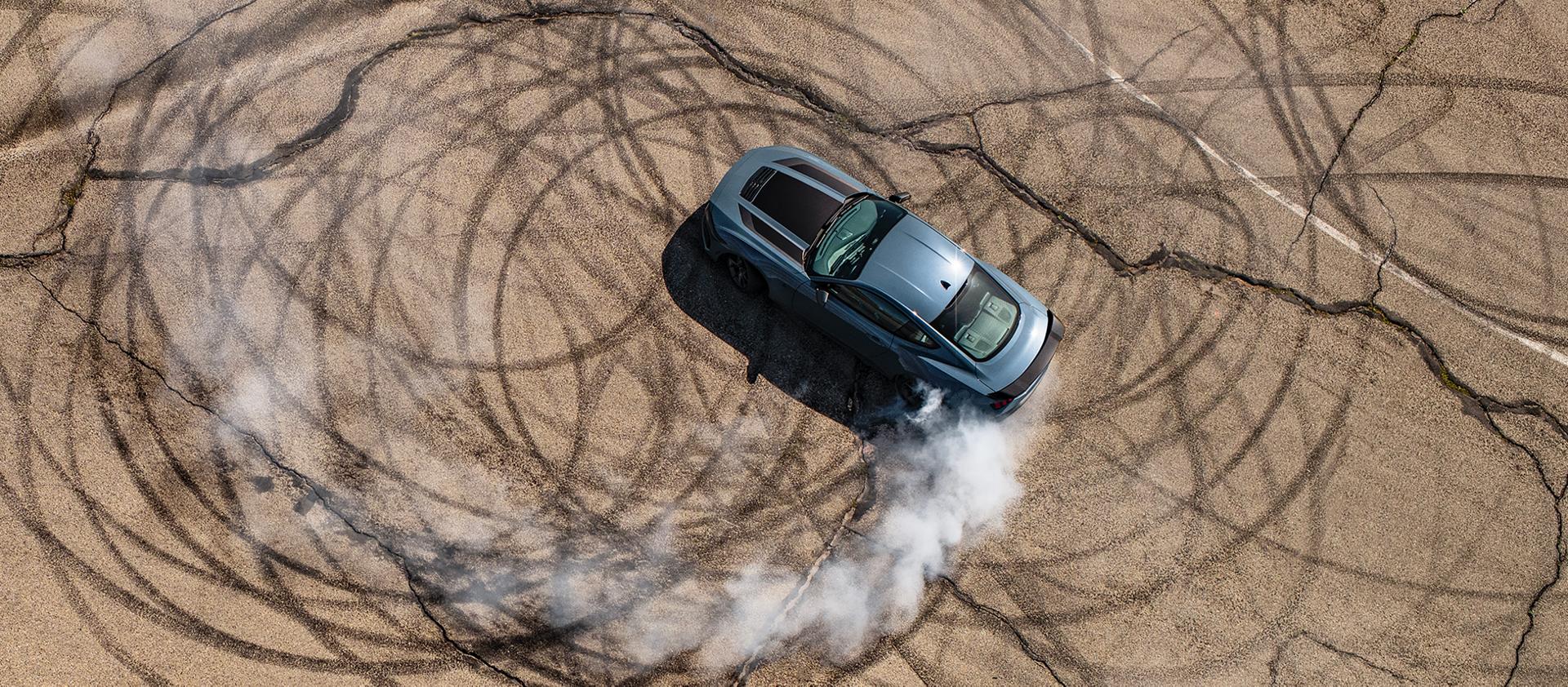 Cupé Ford Mustang® Dark Horse™ 2026 en Vapor Blue Metallic con un conductor que quema ruedas en un circuito cerrado