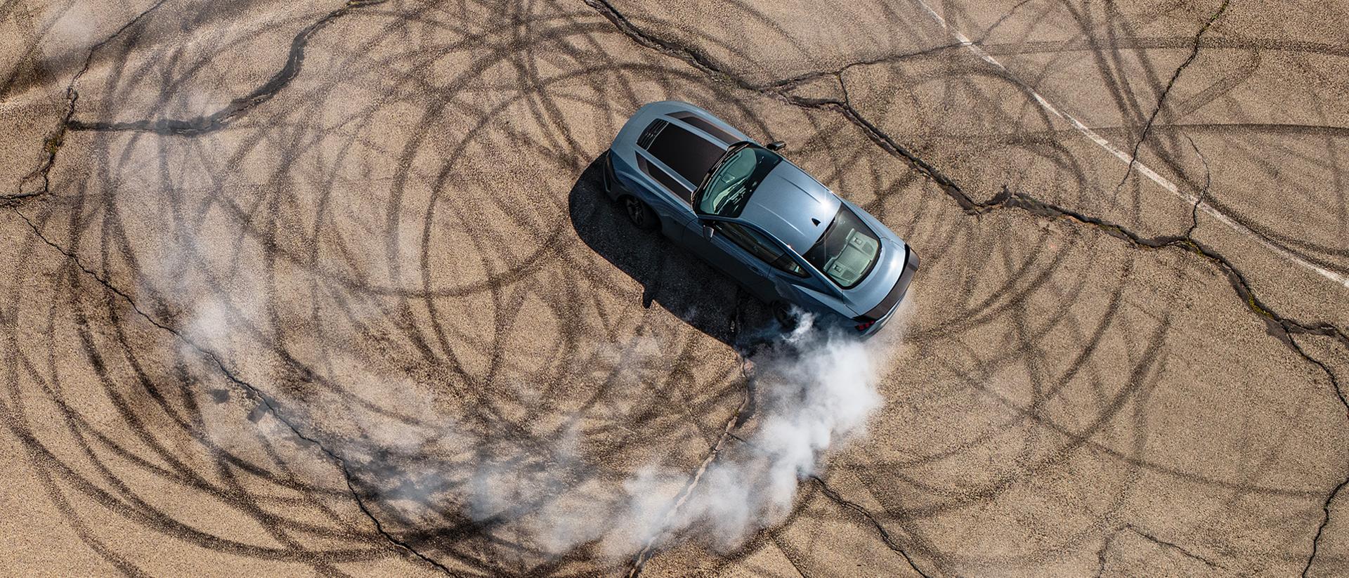 2026 Ford Mustang® Dark Horse™ coupe in Vapor Blue Metallic with a driver performing burnouts on a closed course