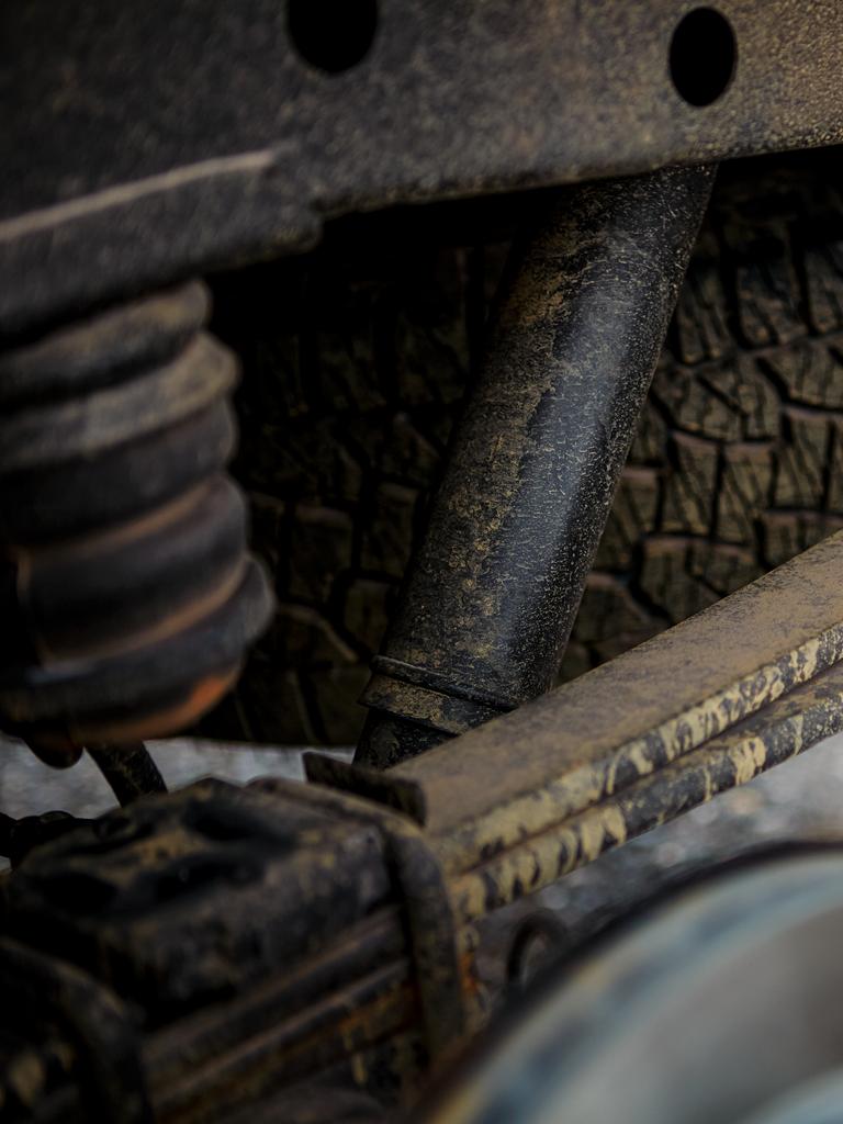 A vehicle's shocks and struts caked with dirt and mud