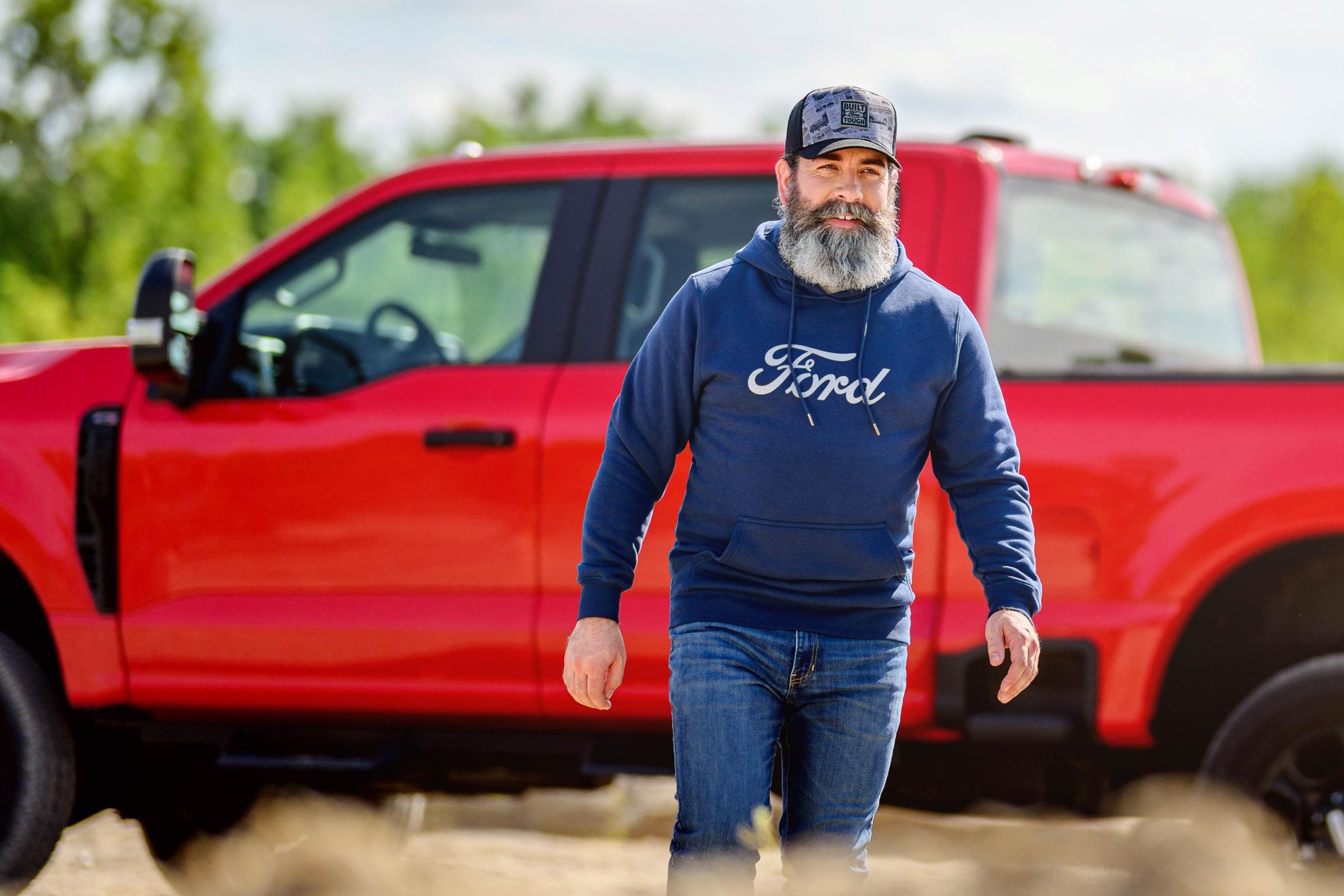 Person in Ford hoodie standing near a red Ford Super Duty® XL truck outdoors
