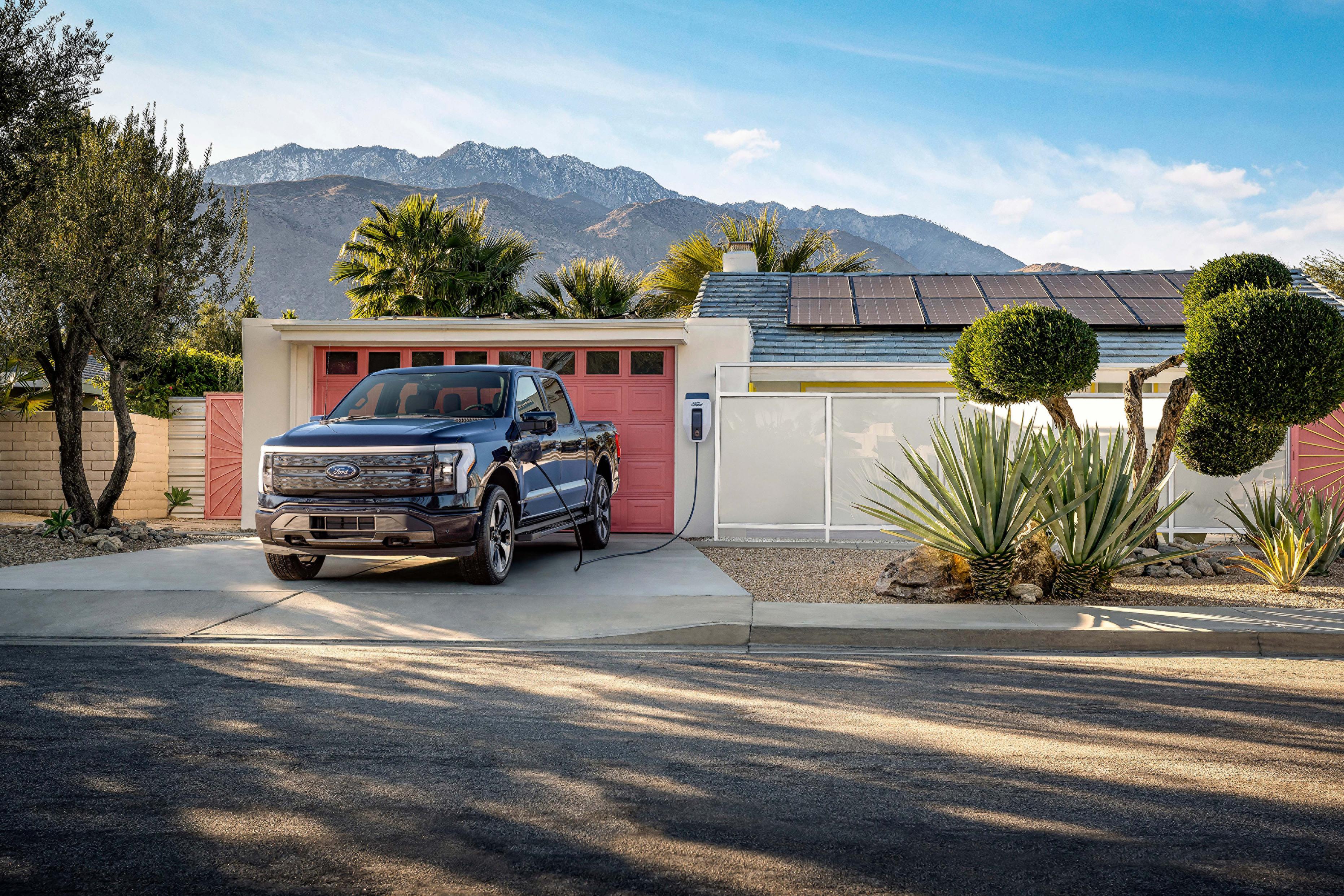 Ford F-150 Lightning truck in driveway while plugged into a Ford Charge Station Pro