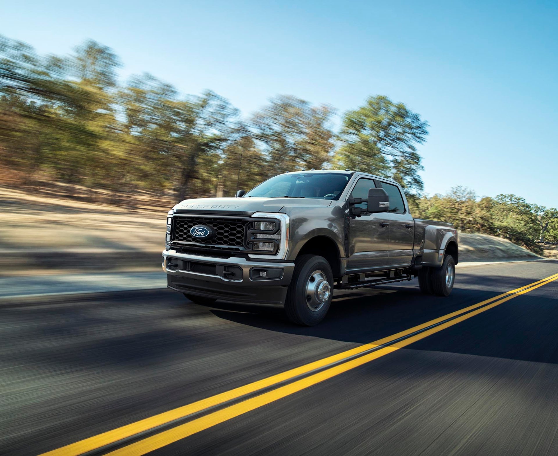 Gray Ford Super Duty F-350 XL dual-rear-wheel pickup driving on a two-lane road