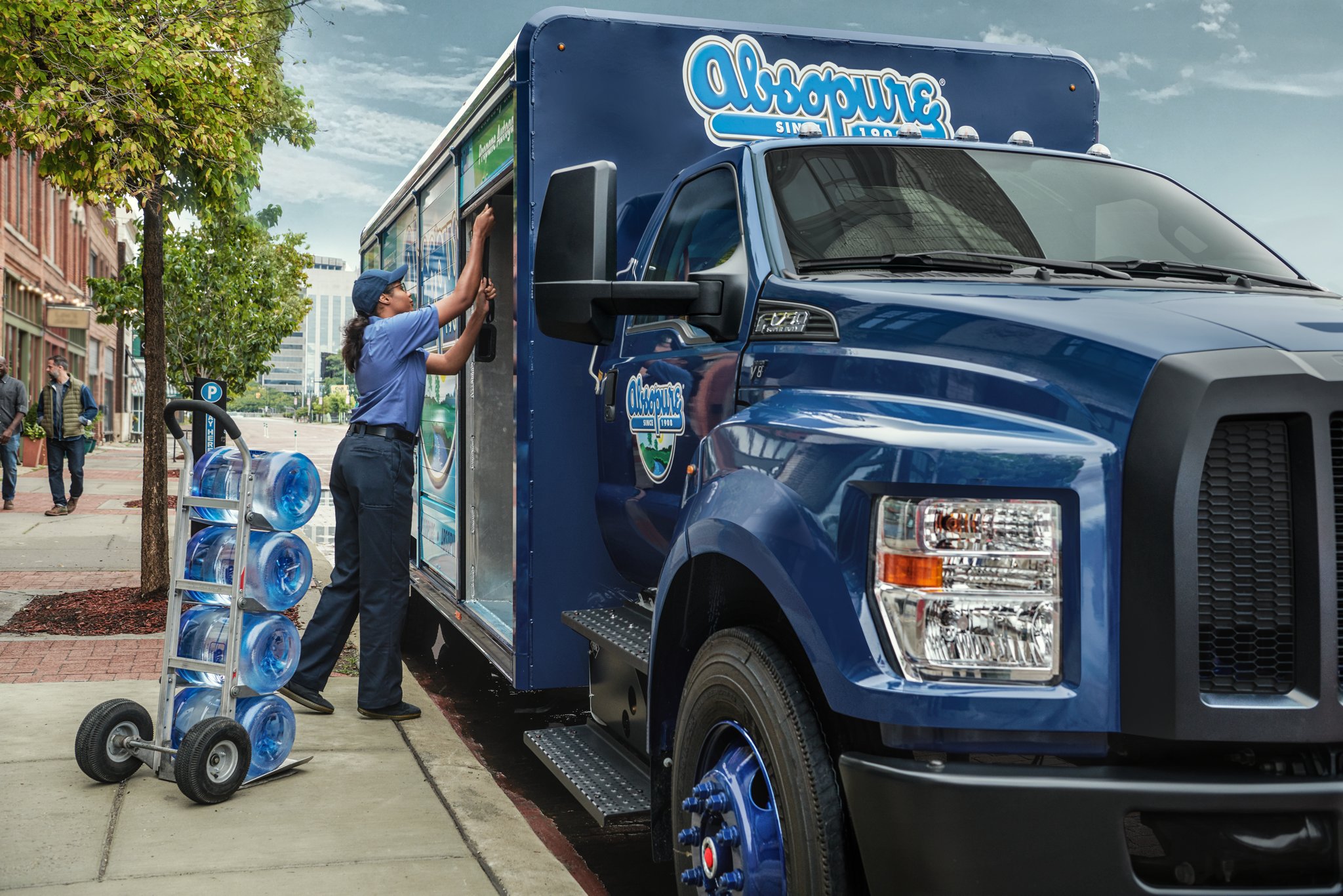 Close-up on worker unloading water from 2026 Ford F-750® Regular Cab in custom design with beverage truck upfit on city street