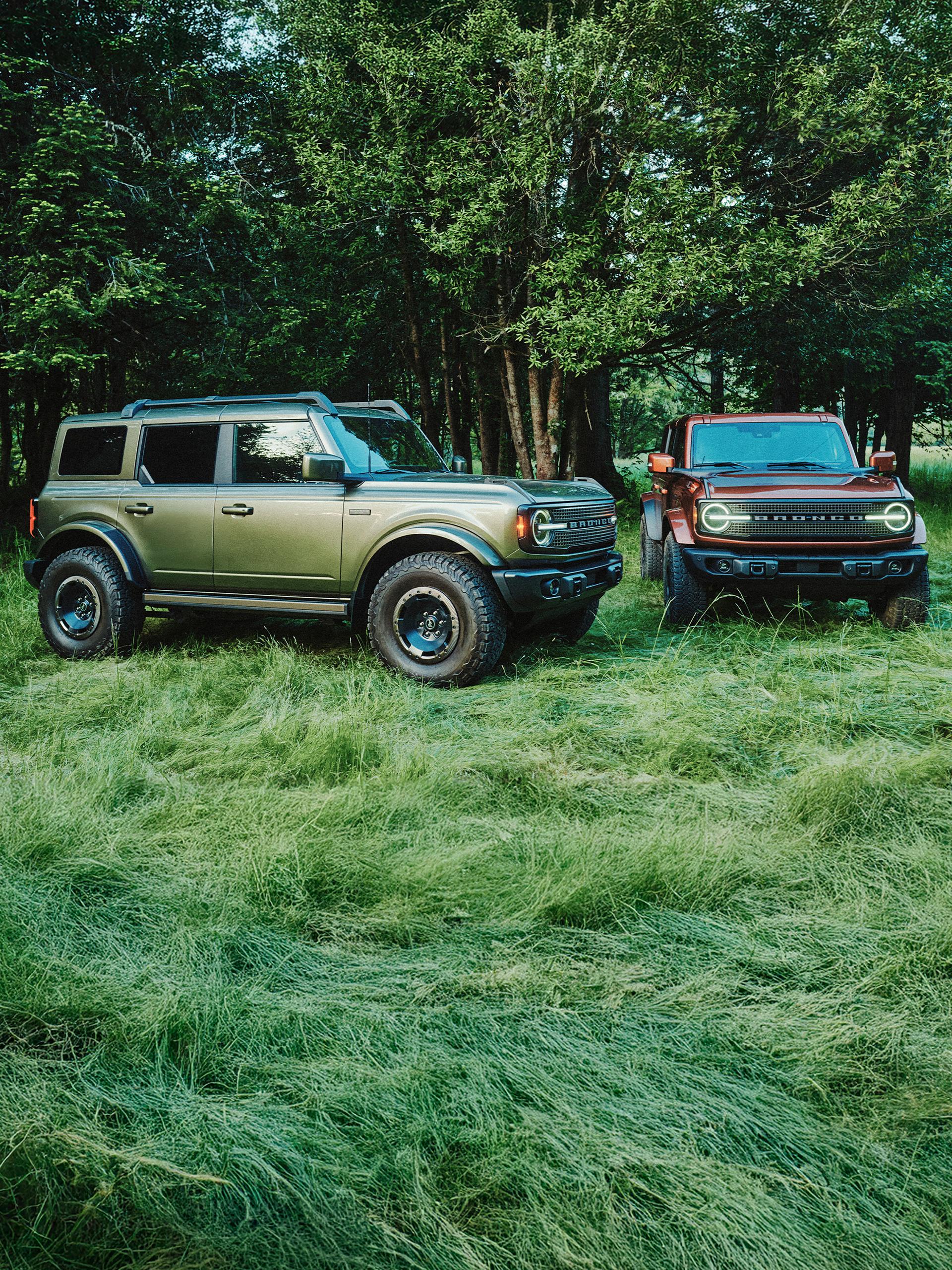 Two 2027 Ford Bronco® Filson SUVs parked in a grassy clearing