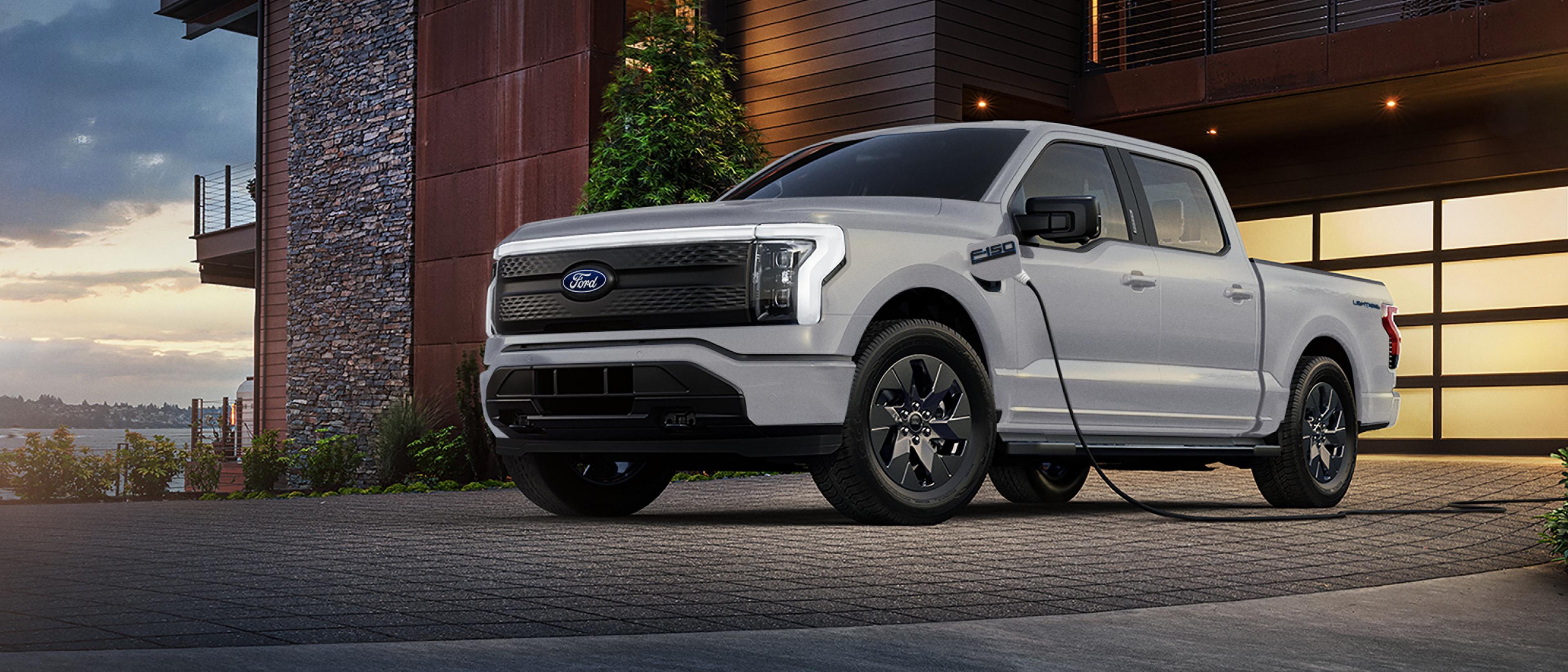 Ford F-150® Lightning® truck charging in the driveway of a modern luxury home