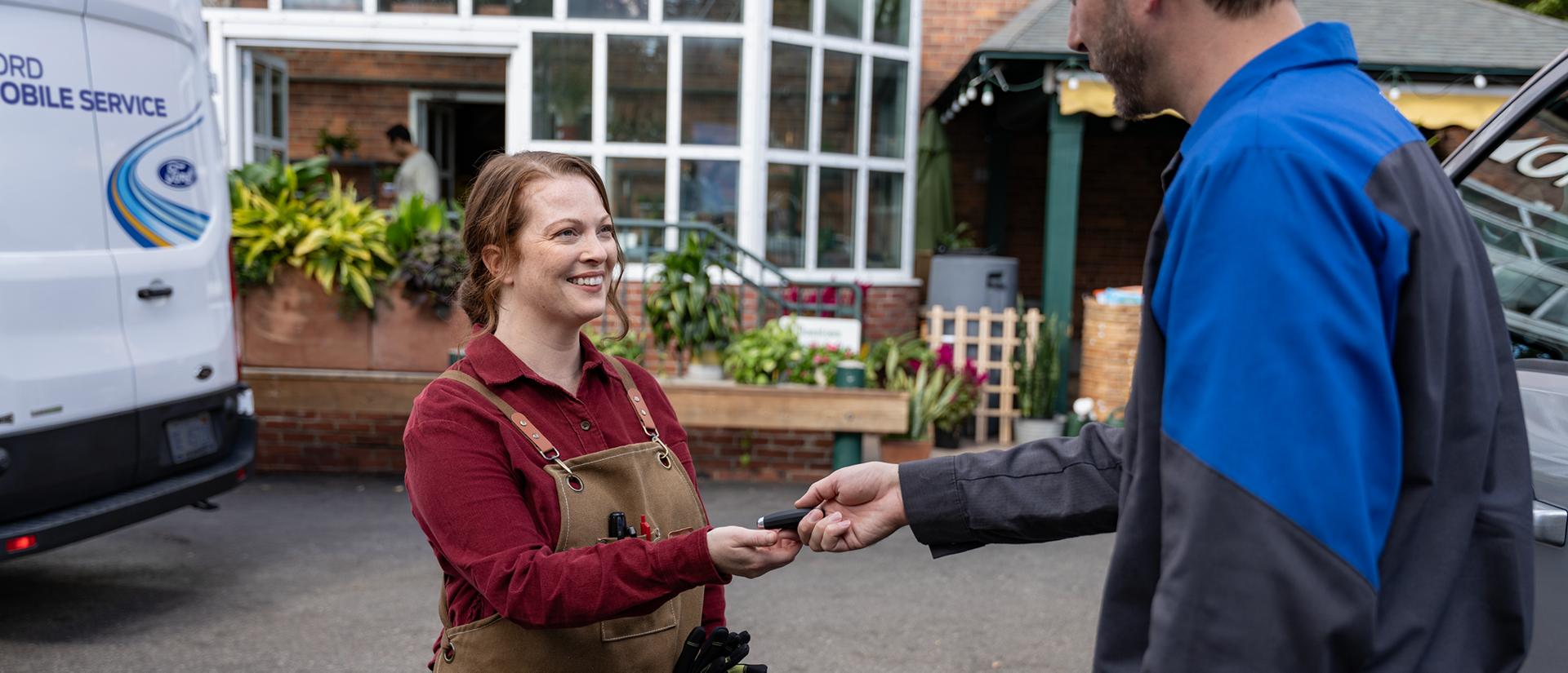 A Ford Mobile Service technician hands keys to a Ford owner