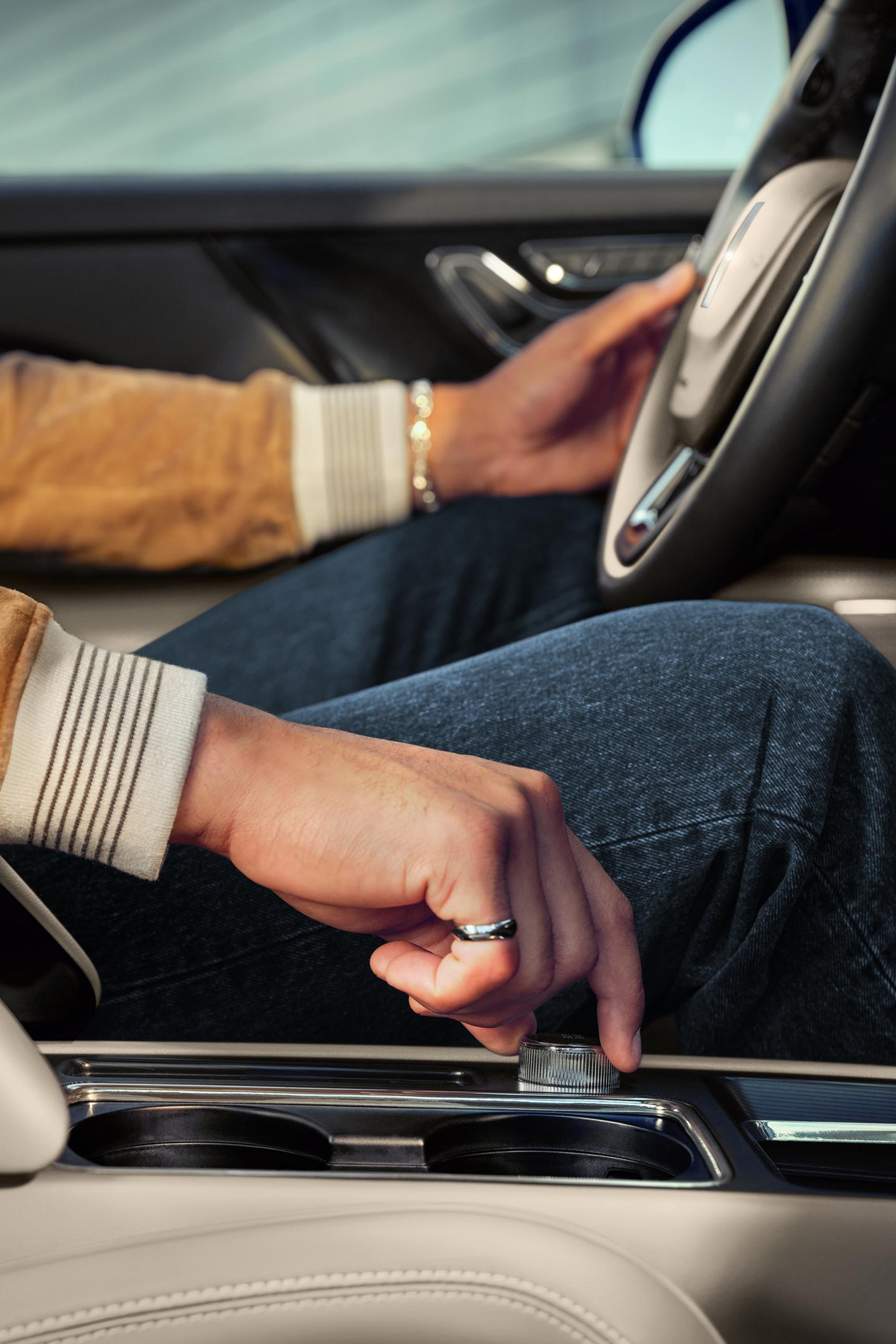A hand of a person driving a 2025 Lincoln Corsair is shown turning a central knob to switch drive modes