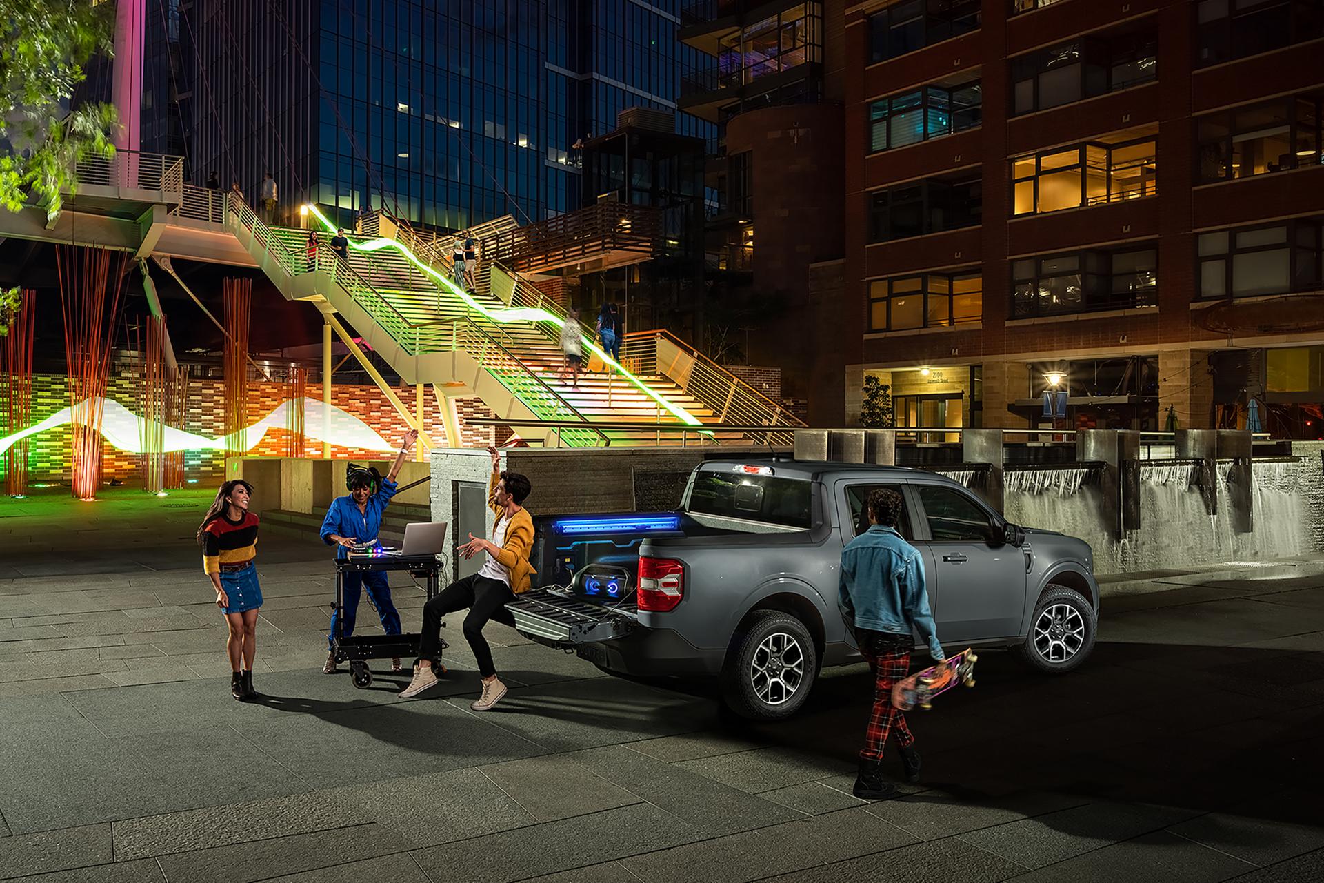 A group of people gathered near a Ford Maverick® pickup with DJ equipment plugged into a cargo bed outlet