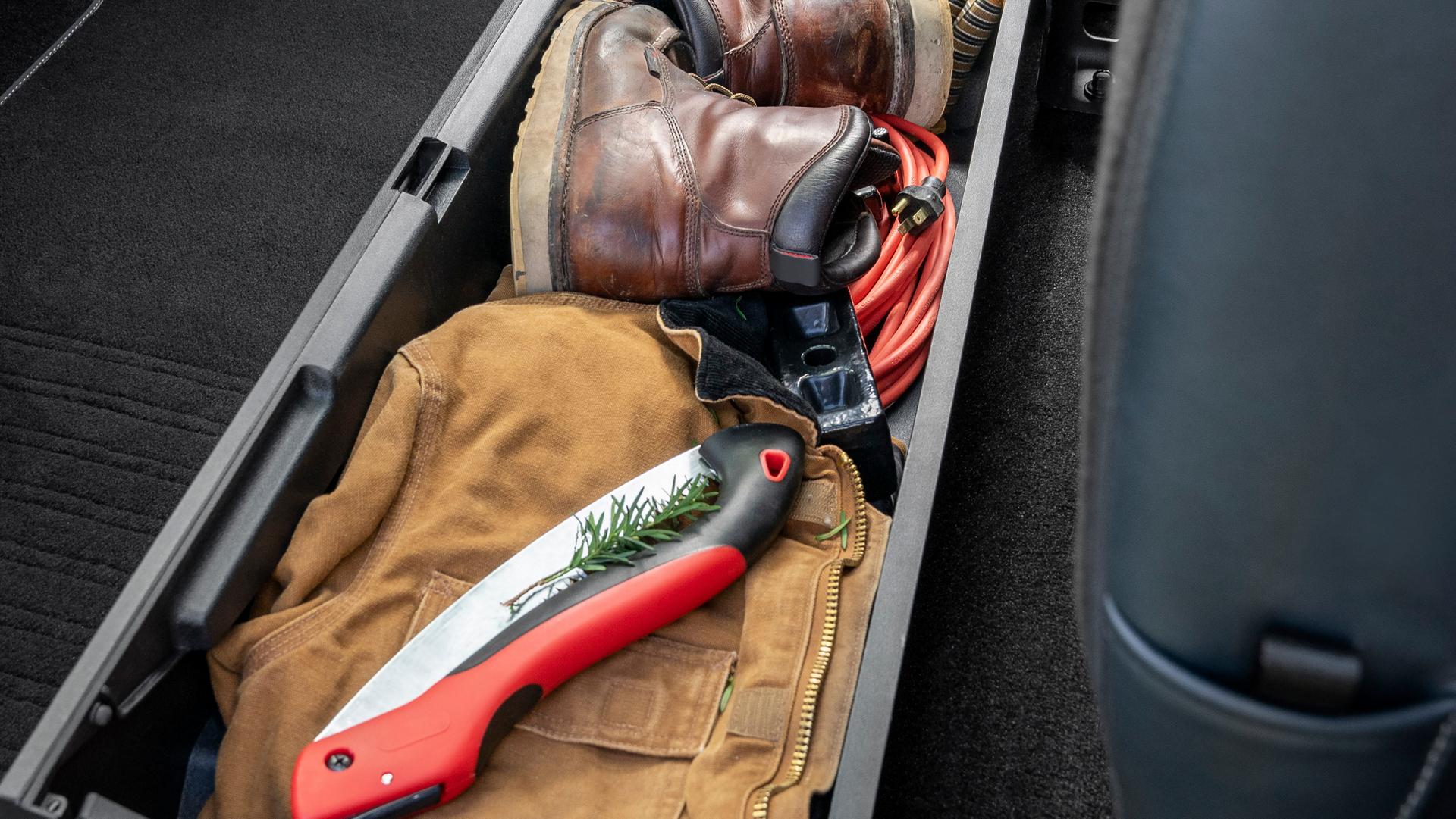Rear under-seat storage box opened and packed with tools and gear