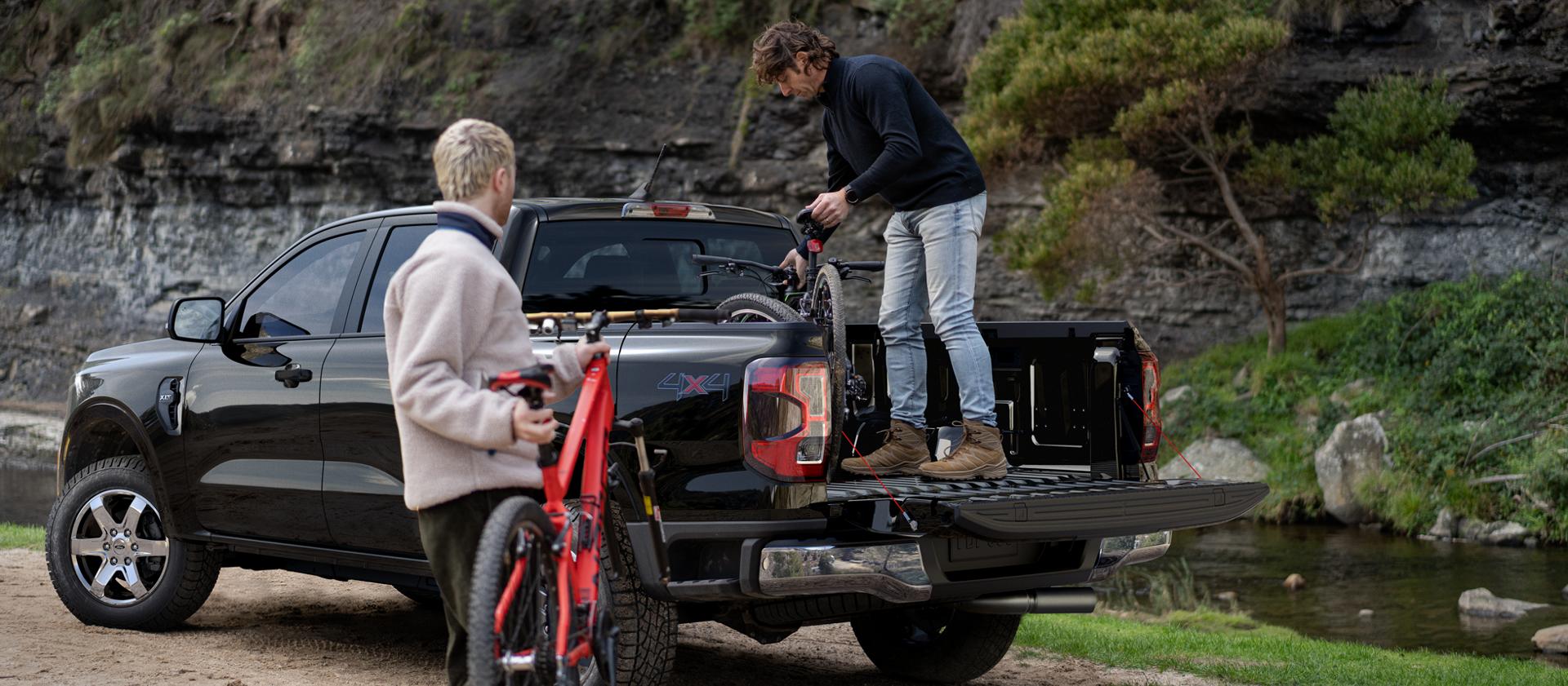 Two people loading gear into the bed of a 2025 Ford Ranger® pickup in Bronze Metallic