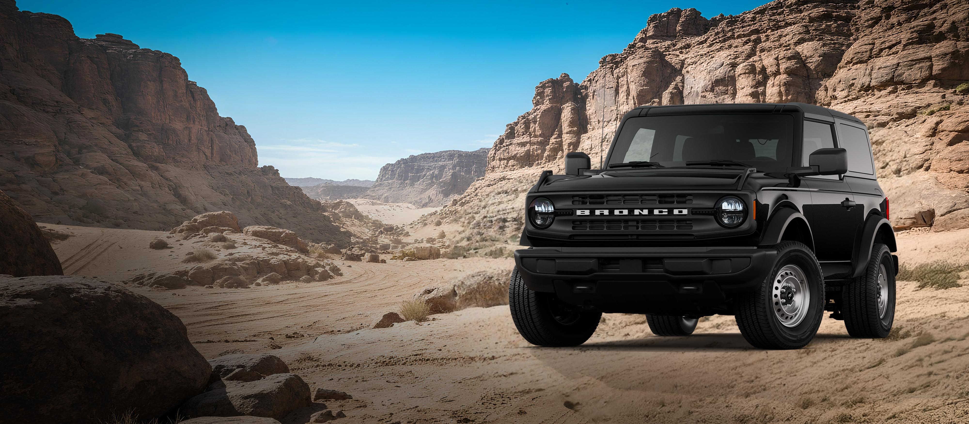 A 2026 Ford Bronco® Base model shown in Shadow Black parked on a rocky expanse