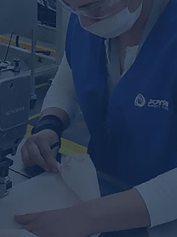 A female Ford employee sewing a protective gown with a sewing machine