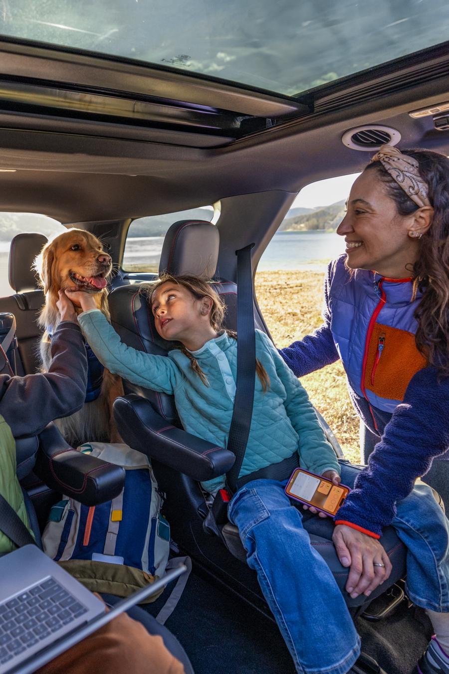 A family and their dog sitting inside a 2025 Ford Explorer® SUV with a lake and mountains in the background