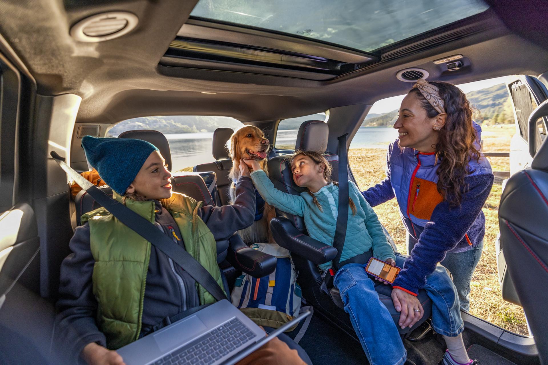 A family and their dog are buckled into their Ford vehicle for a day at the lake