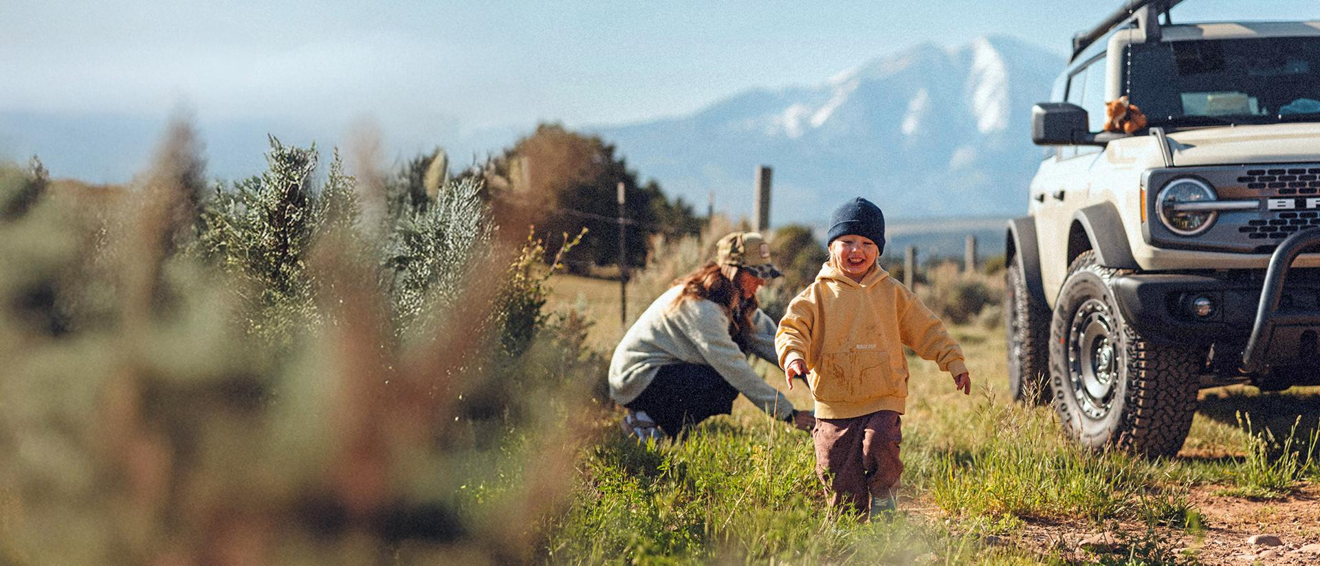 A family, pulled off to the side of the road, stretch their legs in a mountainous landscape