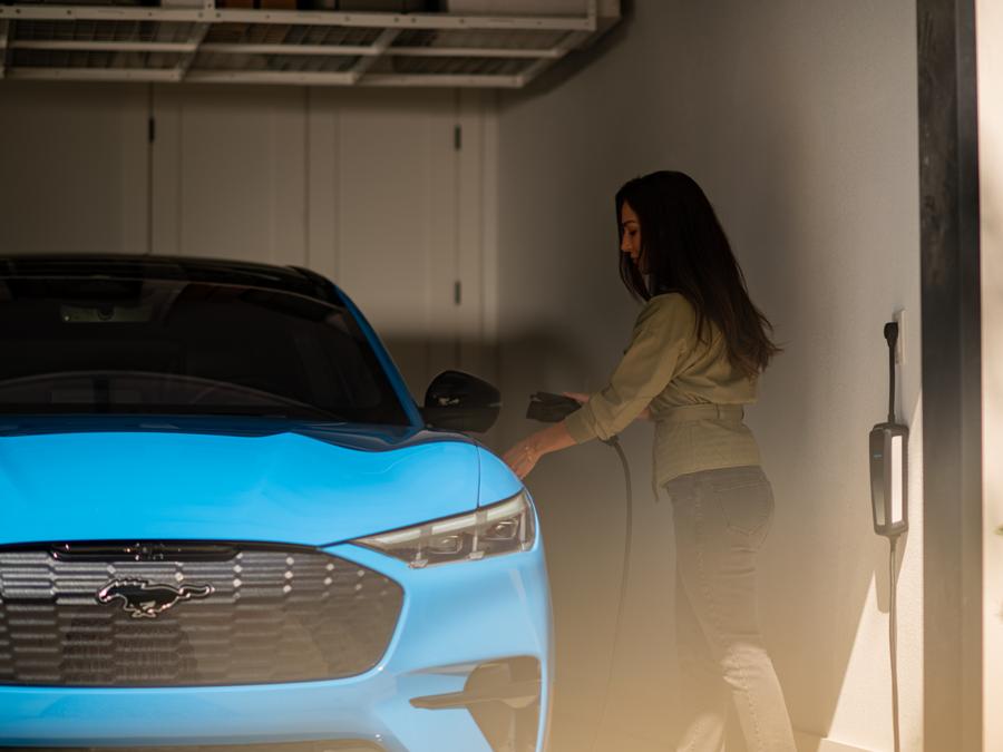 Woman plugging a charger into a Mustang Mach-E® parked in a garage