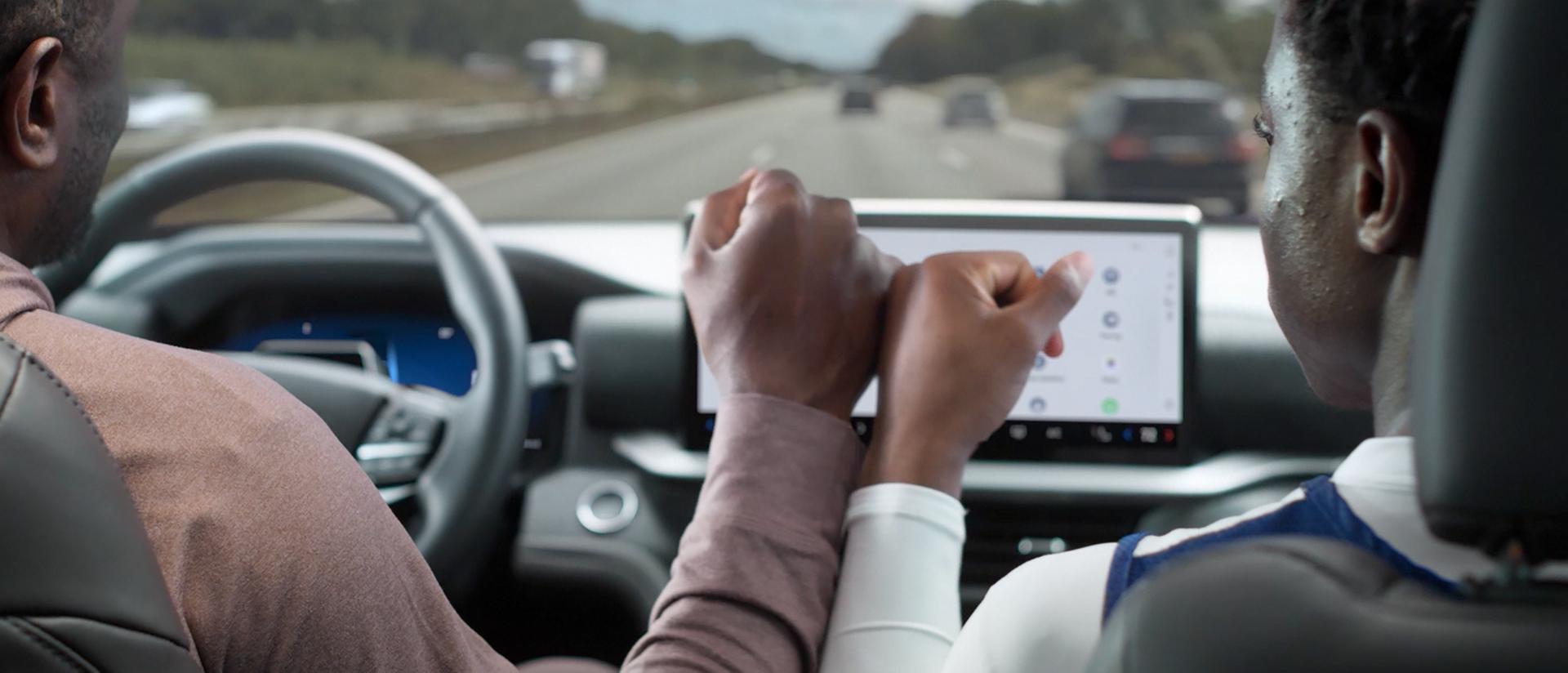 A driver and passenger touching hands in a 2026 Ford Explorer® SUV while BlueCruise is active