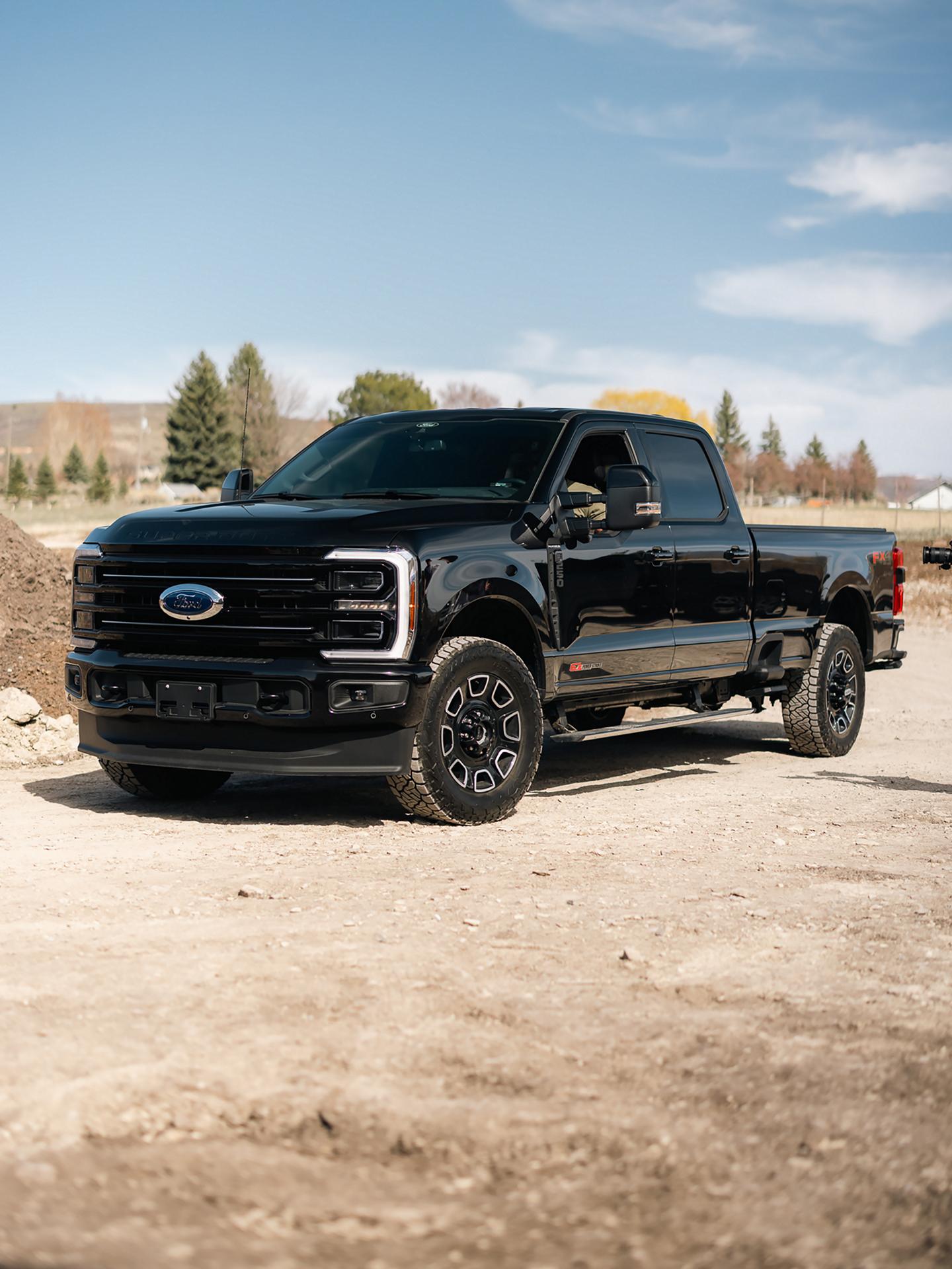 A 2025 Ford Super Duty® parked on a gravel road with a wooded hillside in the background