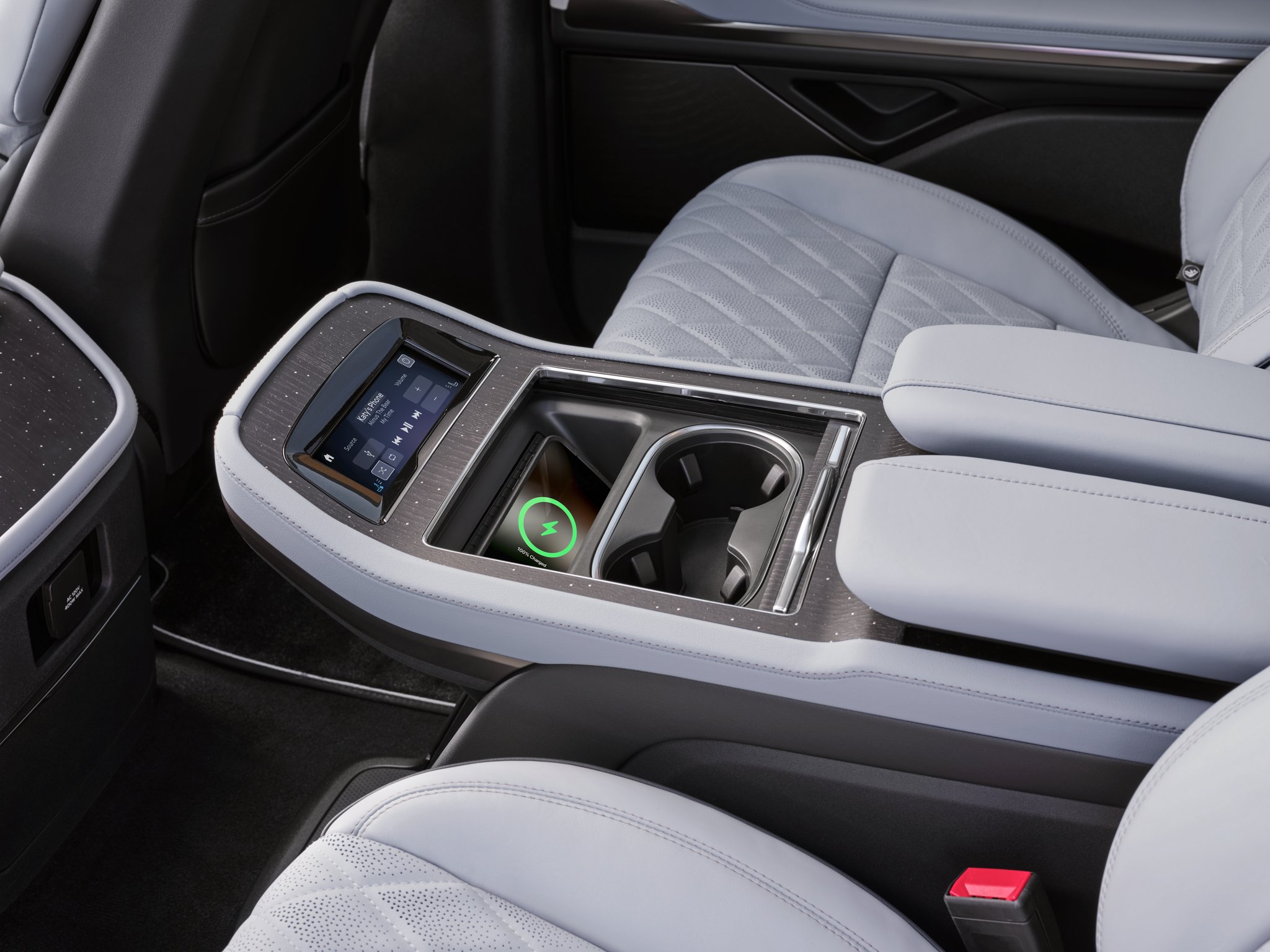 A phone charges on a wireless charging pad in the second row console of a 2025 Lincoln Black Label Navigator.