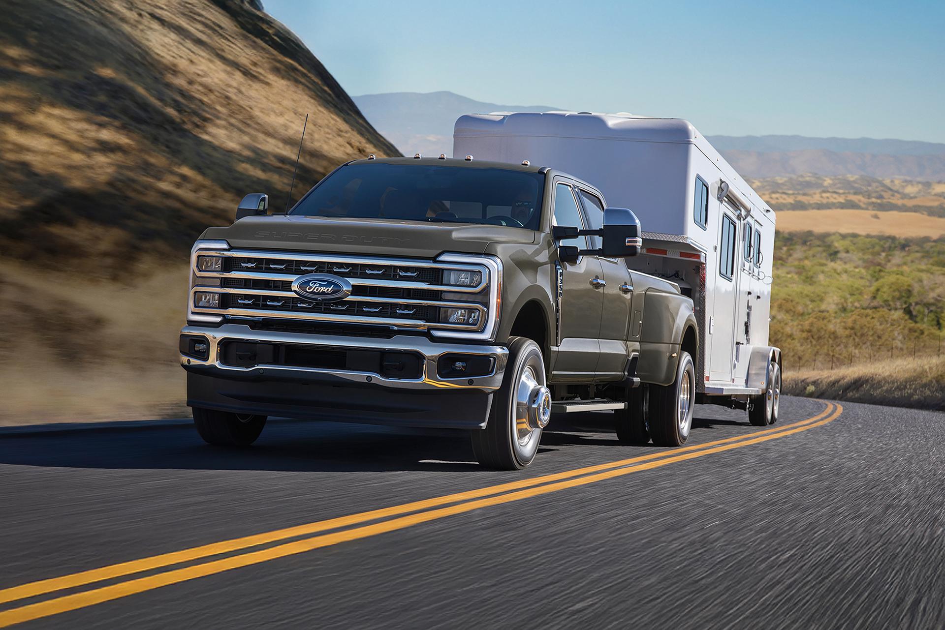 A gray Ford Super Duty® truck towing a camper down a mountain-lined highway