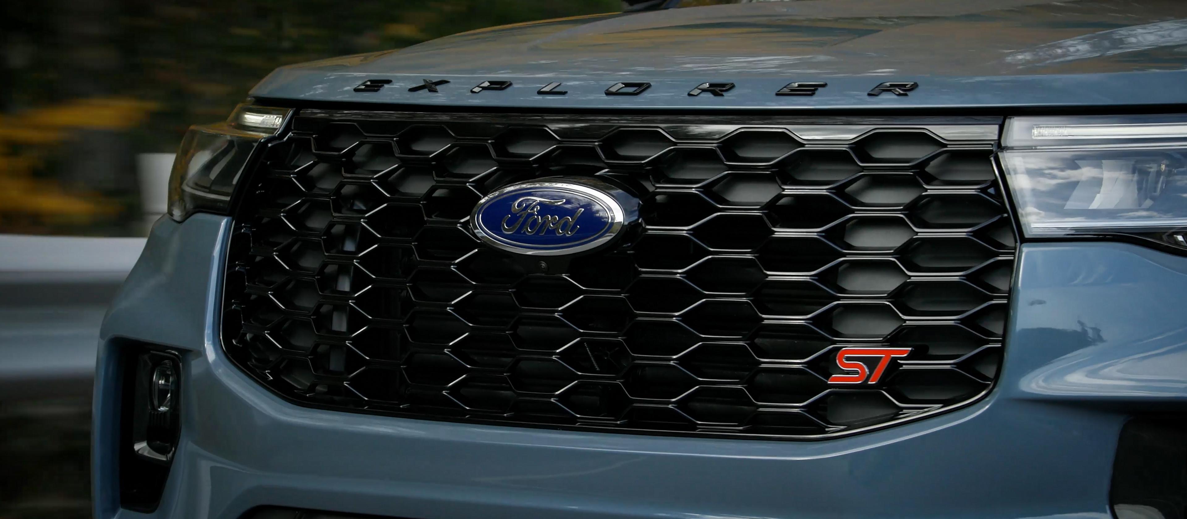 A 2026 Ford Explorer® Tremor® SUV pulling a trailer of recreational equipment down a dirt road