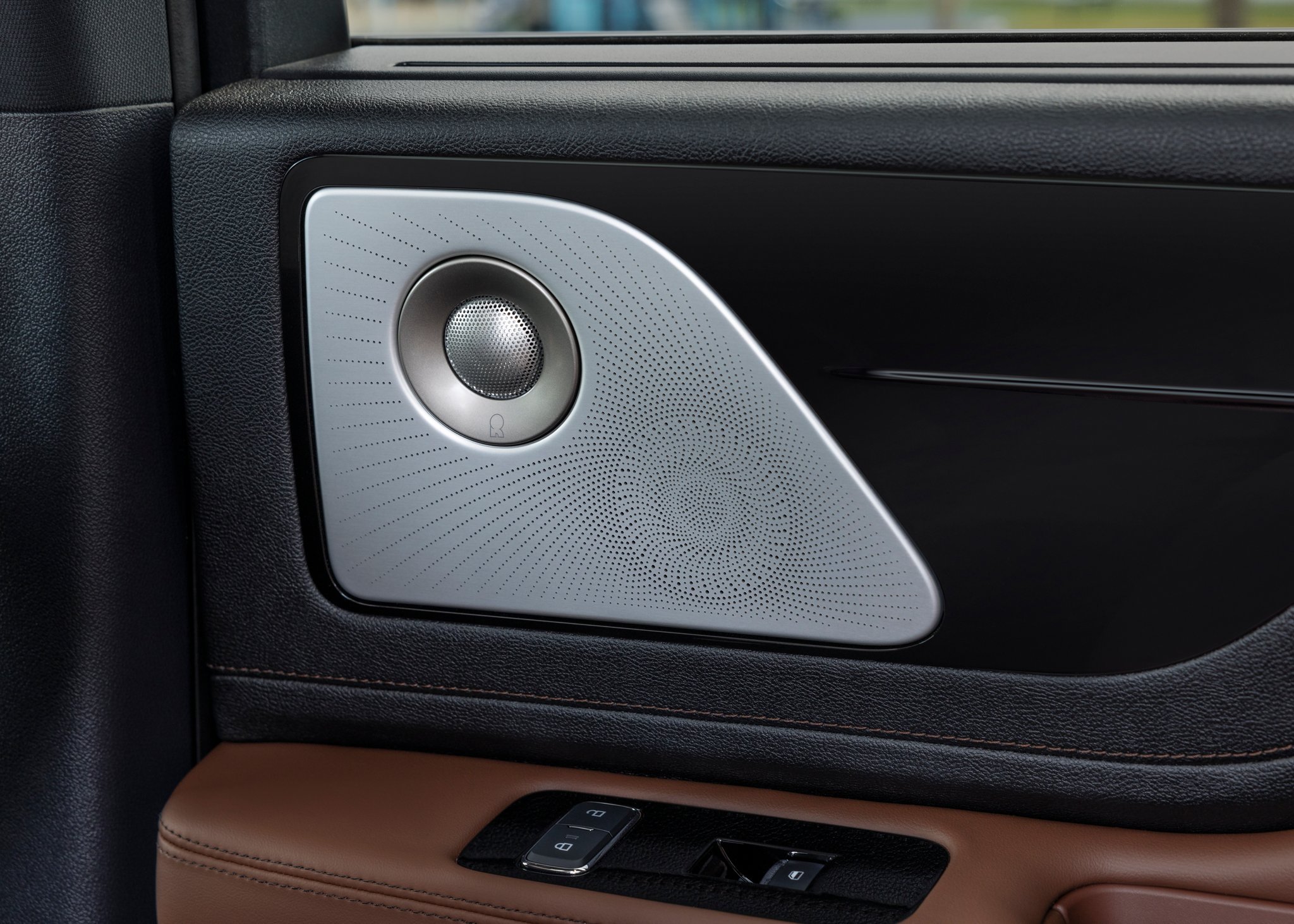A Revel® speaker is shown on the interior door panel of a 2025 Lincoln Aviator® SUV.