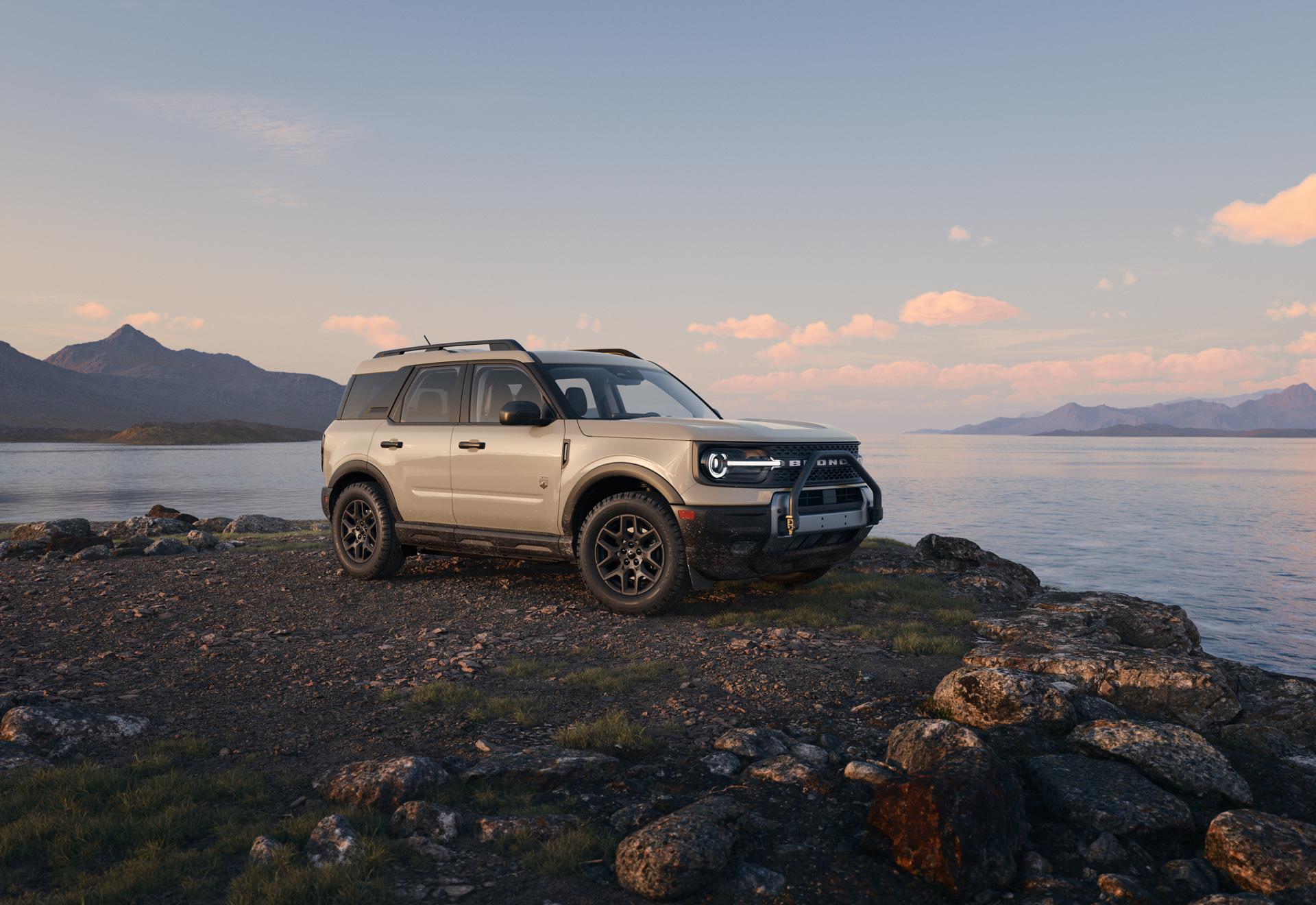 A 2025 Ford Bronco Sport® Big Bend® SUV parked near the edge of a lake with mountains in the distance