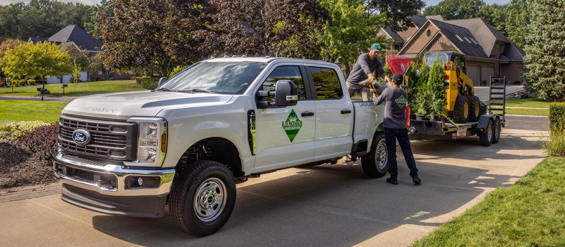 2027 Ford Super Duty® truck parked in a driveway towing a large trailer with equipment for landscaping