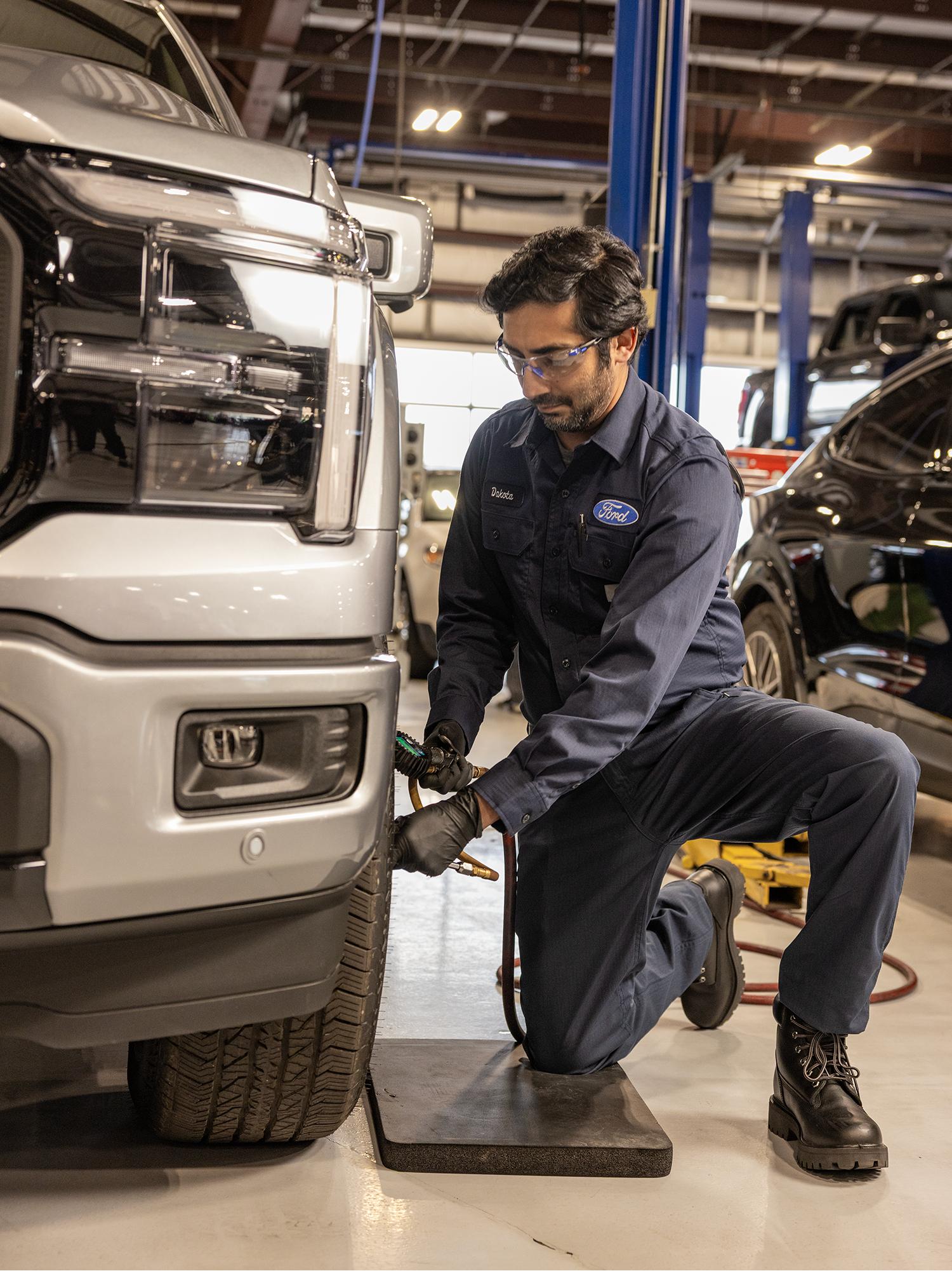 A Ford Service technician works on a truck