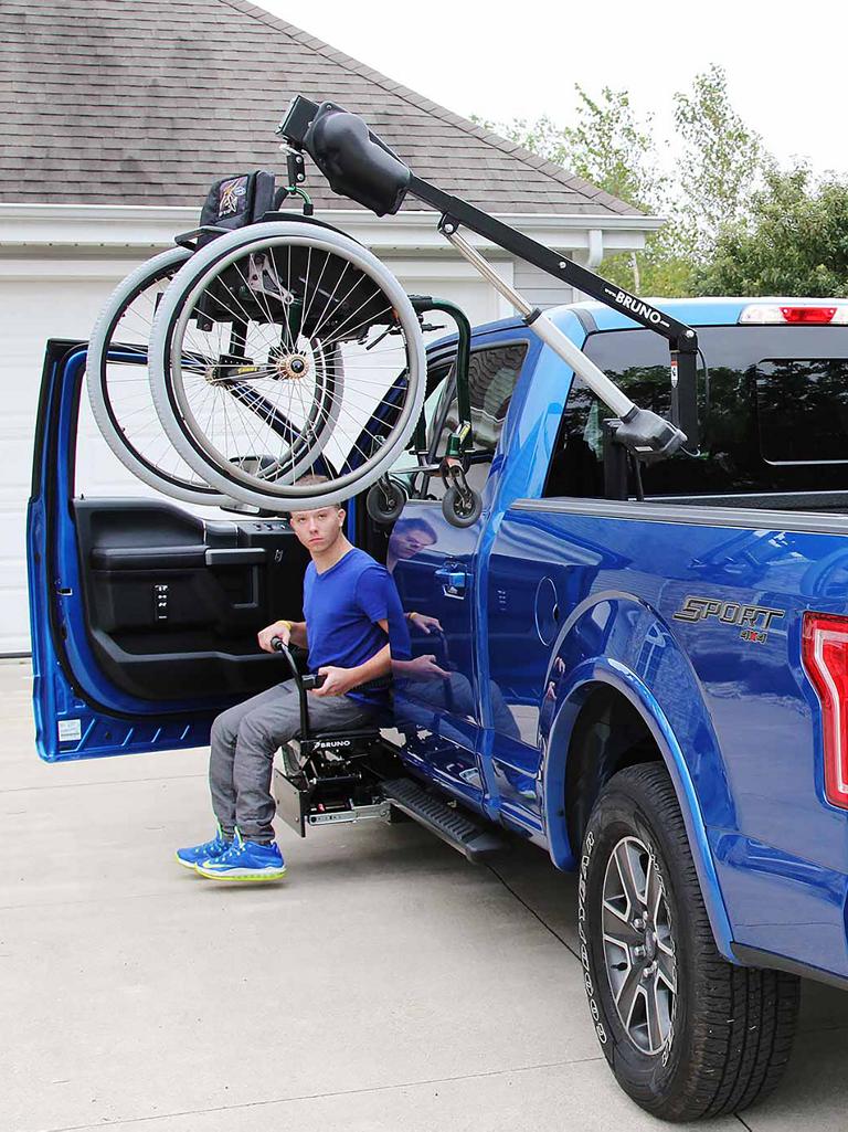 A blue F-150 with a wheelchair hoist in the bed