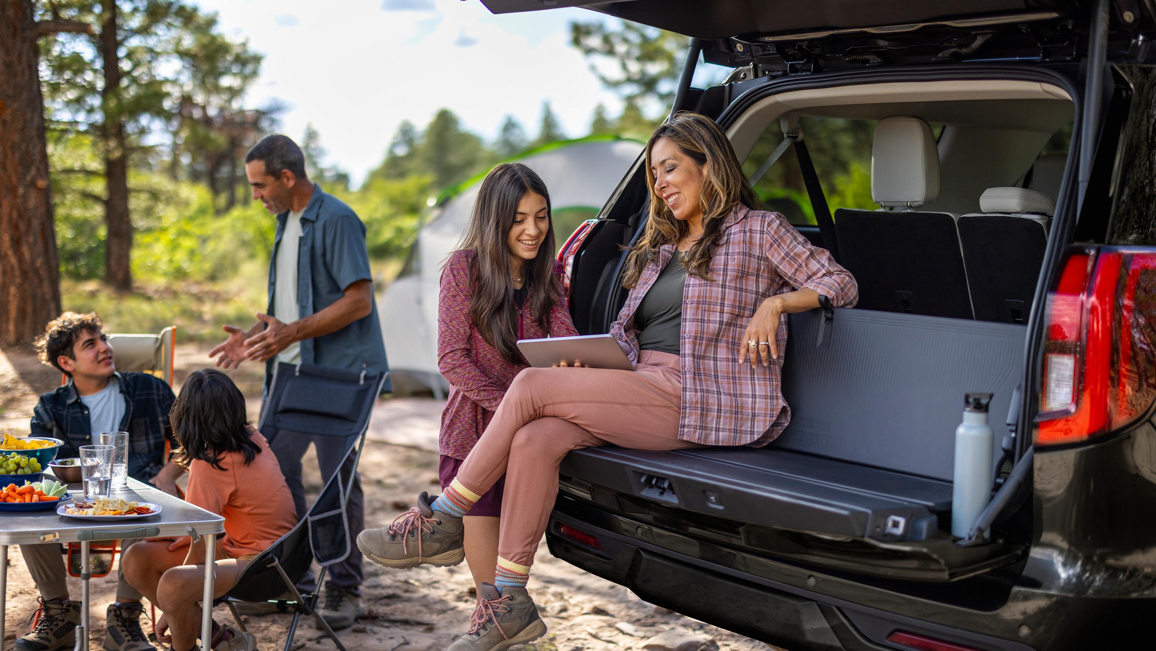 Two people using the available tailgate backrest in a 2027 Ford Expedition® SUV