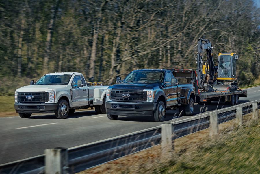 Ford Super Duty® F-350® XL RAJ 2025 en blanc Oxford et F-450® XL à RAJ en bleu antimatière circulant sur une route pavée