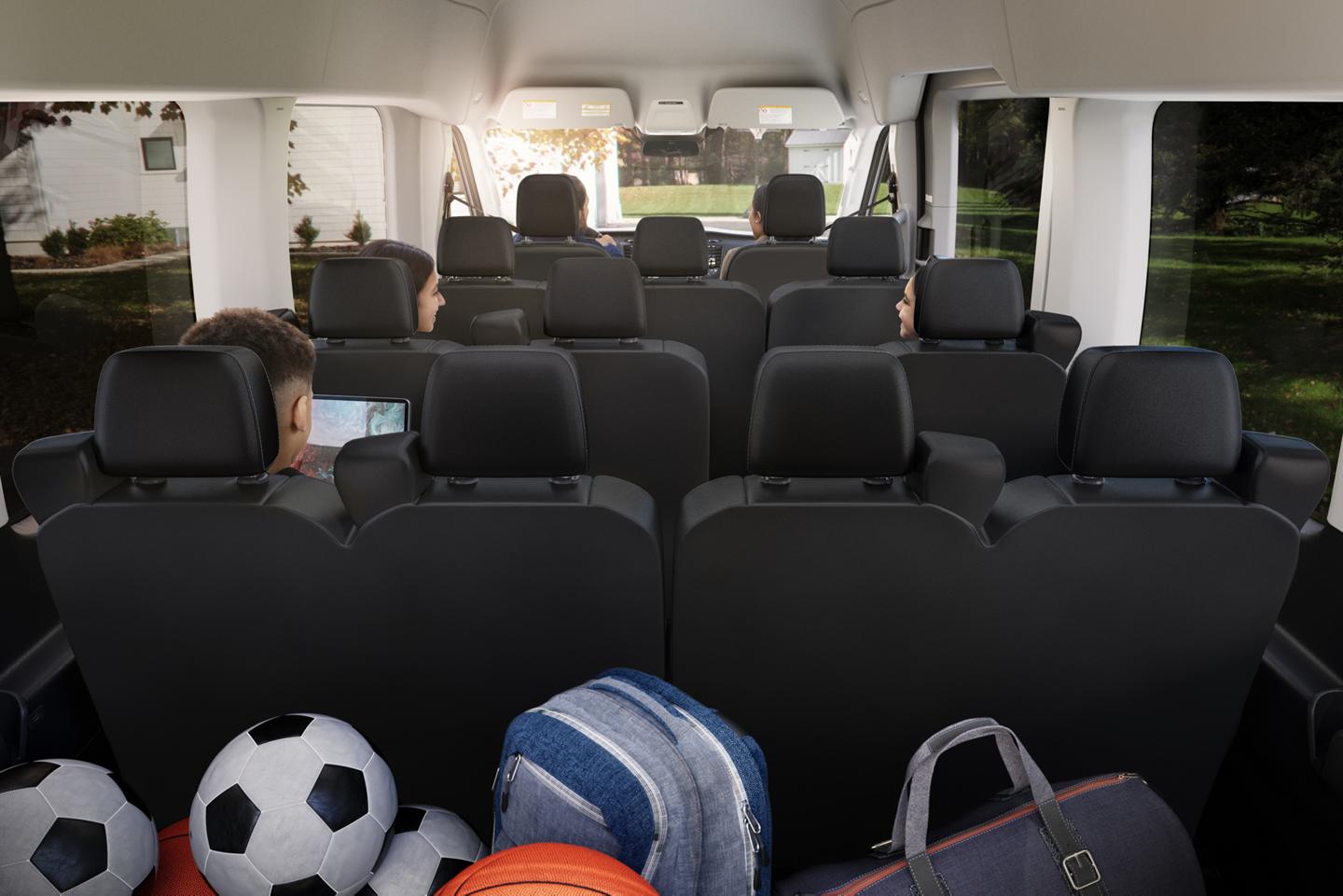 Interior of a 2027 Ford Transit® passenger van with multiple rows of black seats occupied by children, viewed from the back