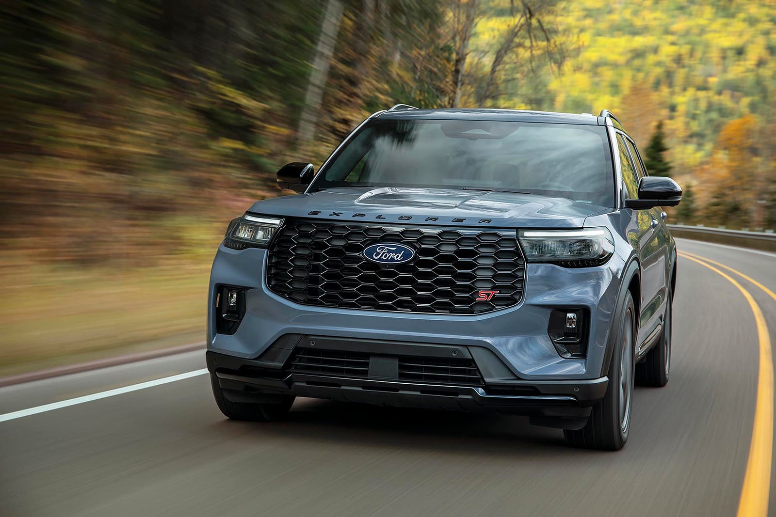 2027 Ford Explorer ST driving on a forest highway showing its sport-tuned stance