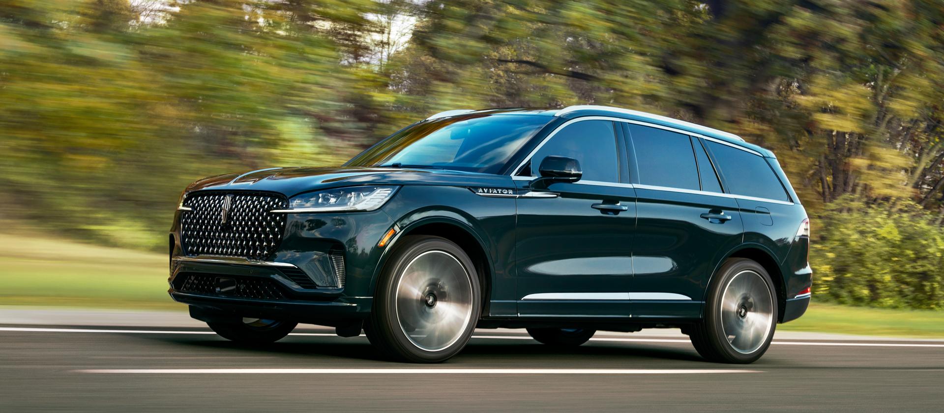 A 2025 Lincoln Aviator® SUV is shown driving on a forested road