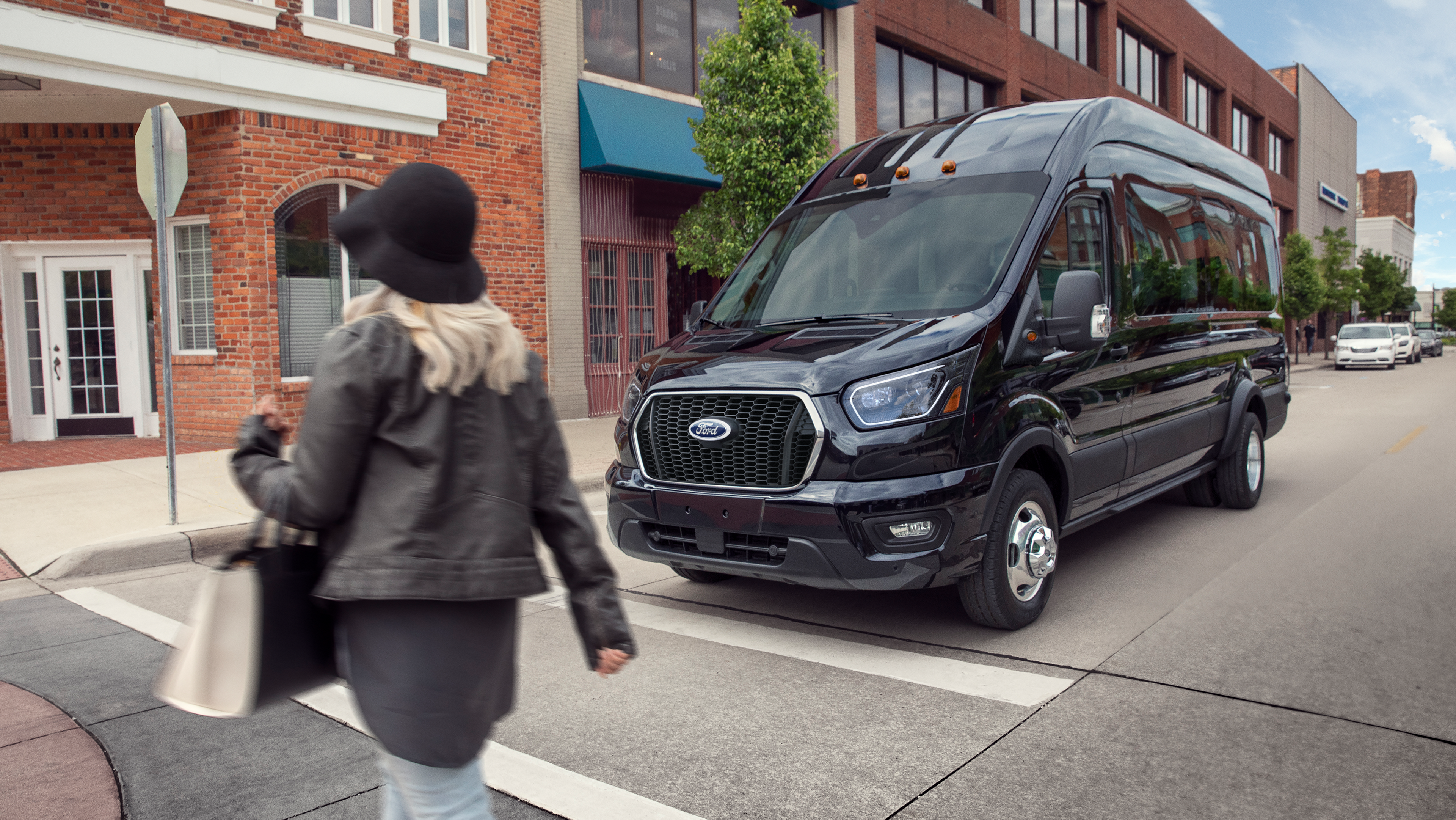 A 2026 Ford Transit® van stopped at a stop sign waiting for pedestrian to cross