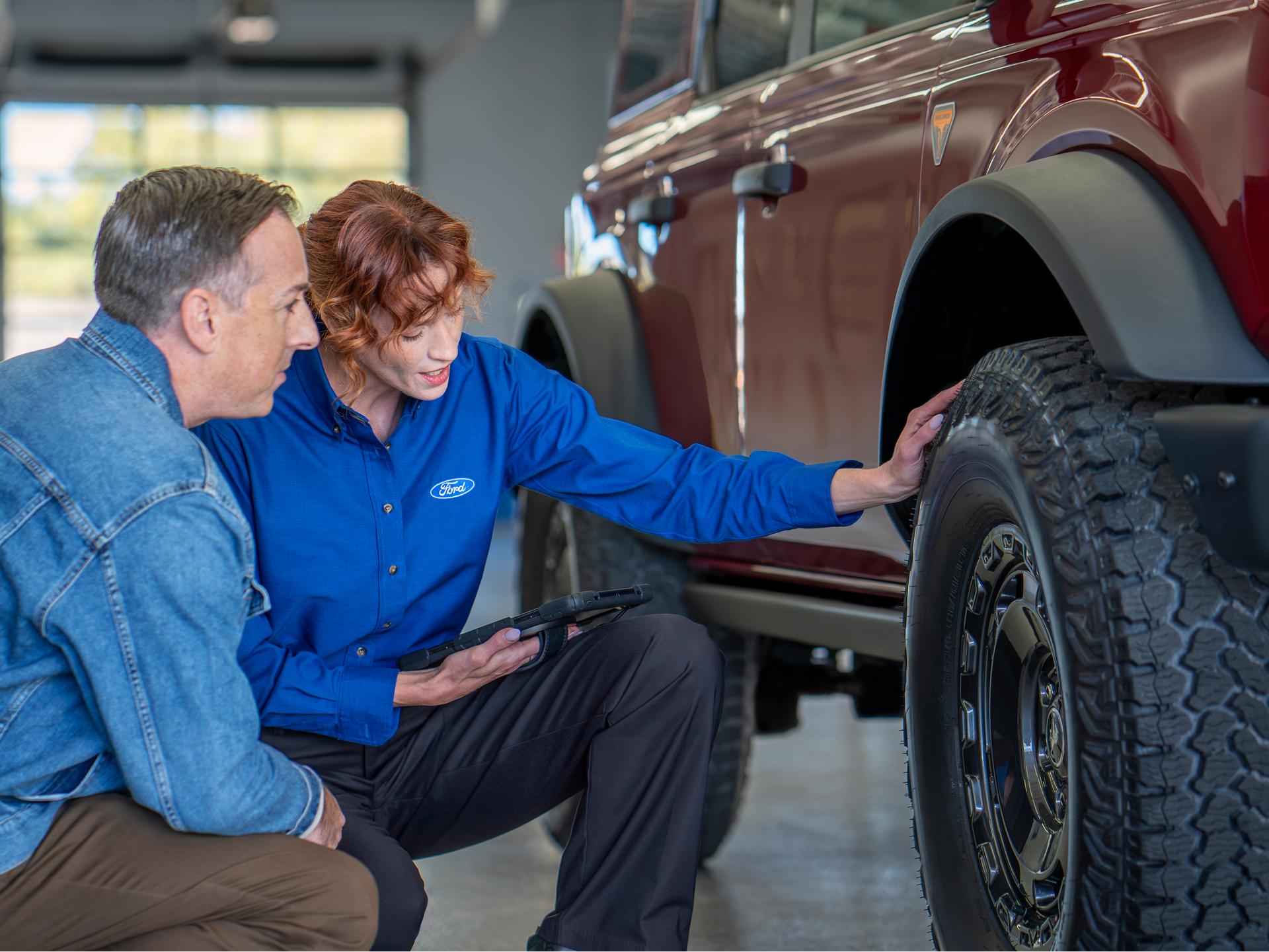 A Ford Service representative and Ford customer check the tread on a tire