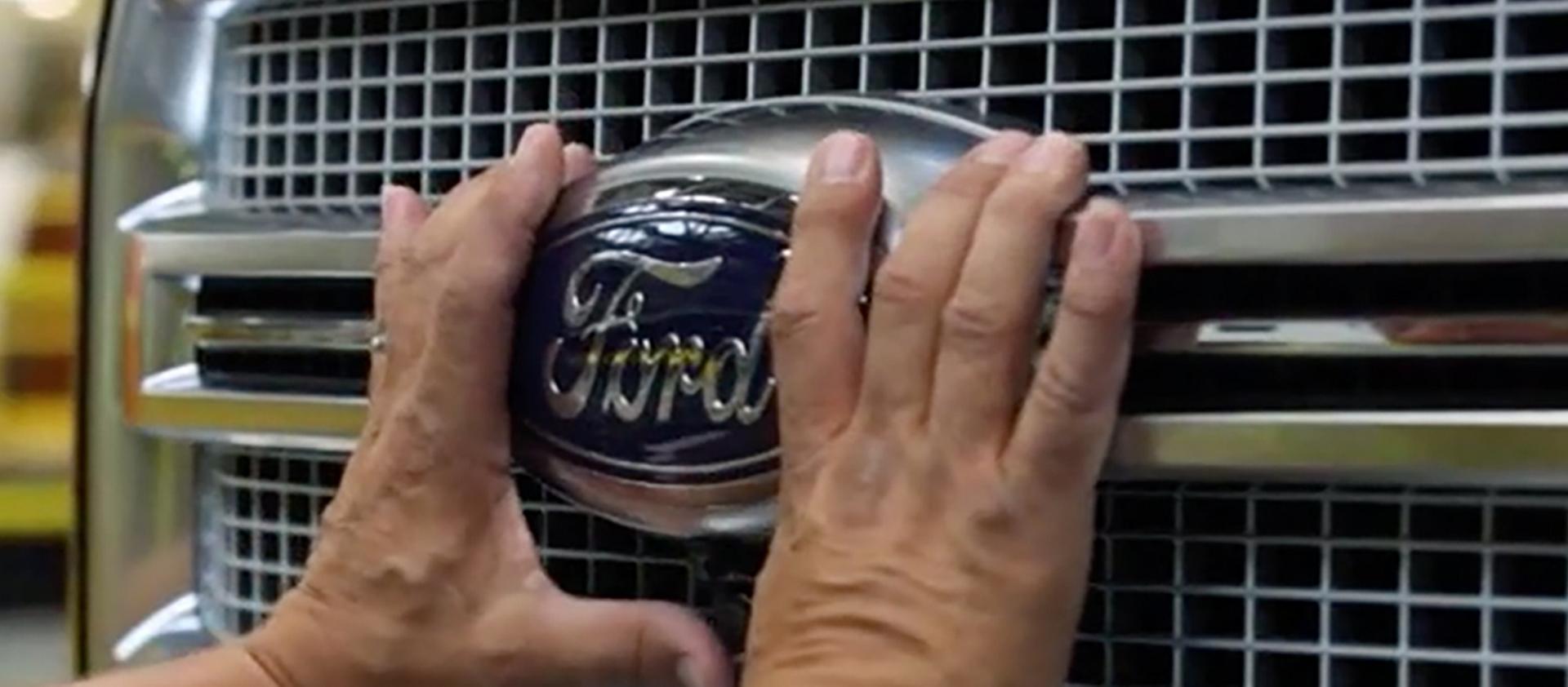 Man touching front grill and Ford logo