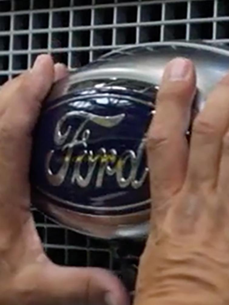 Man touching front grill and Ford logo