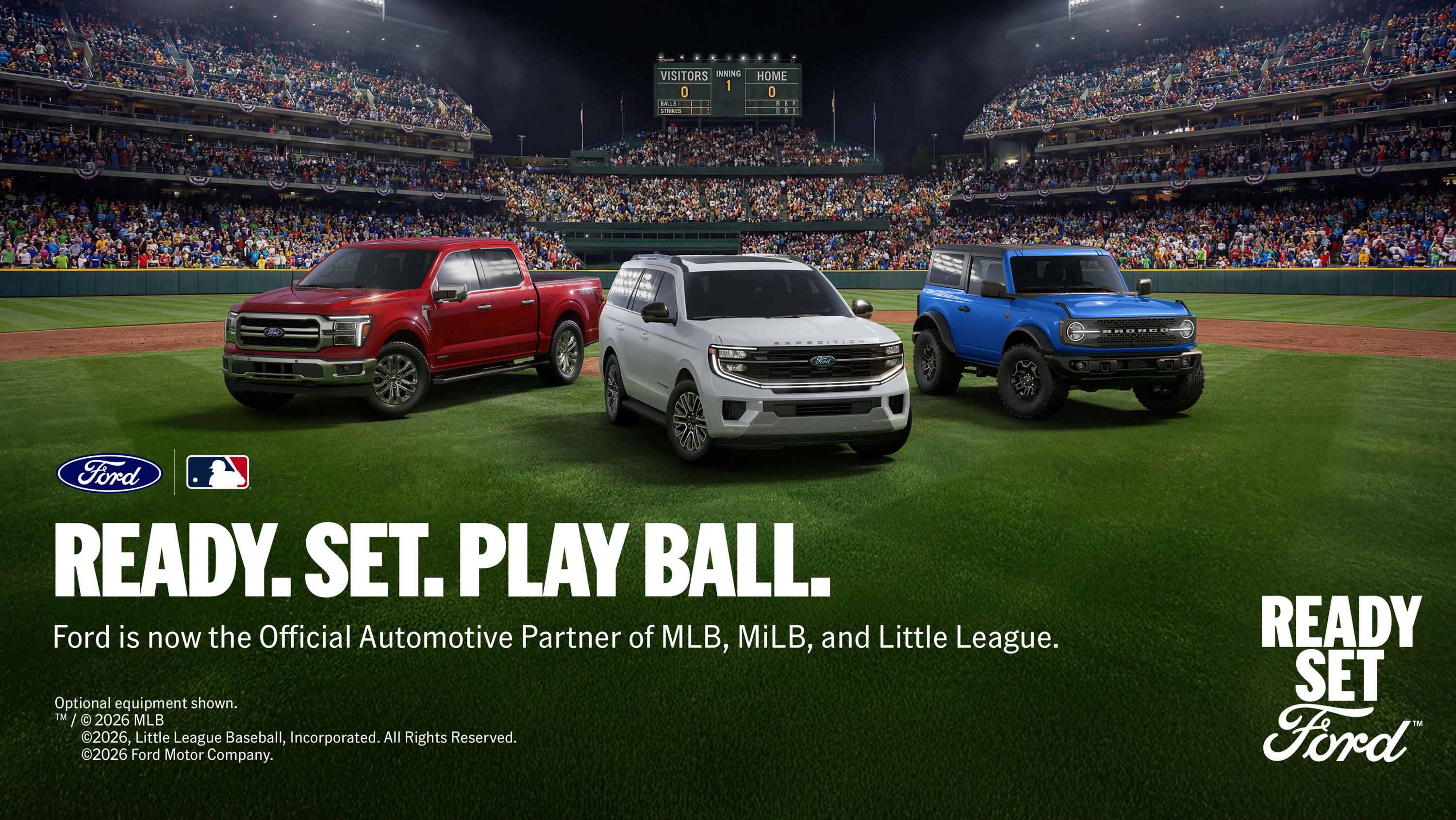 A lineup of 2026 Ford vehicles on a baseball field inside a stadium