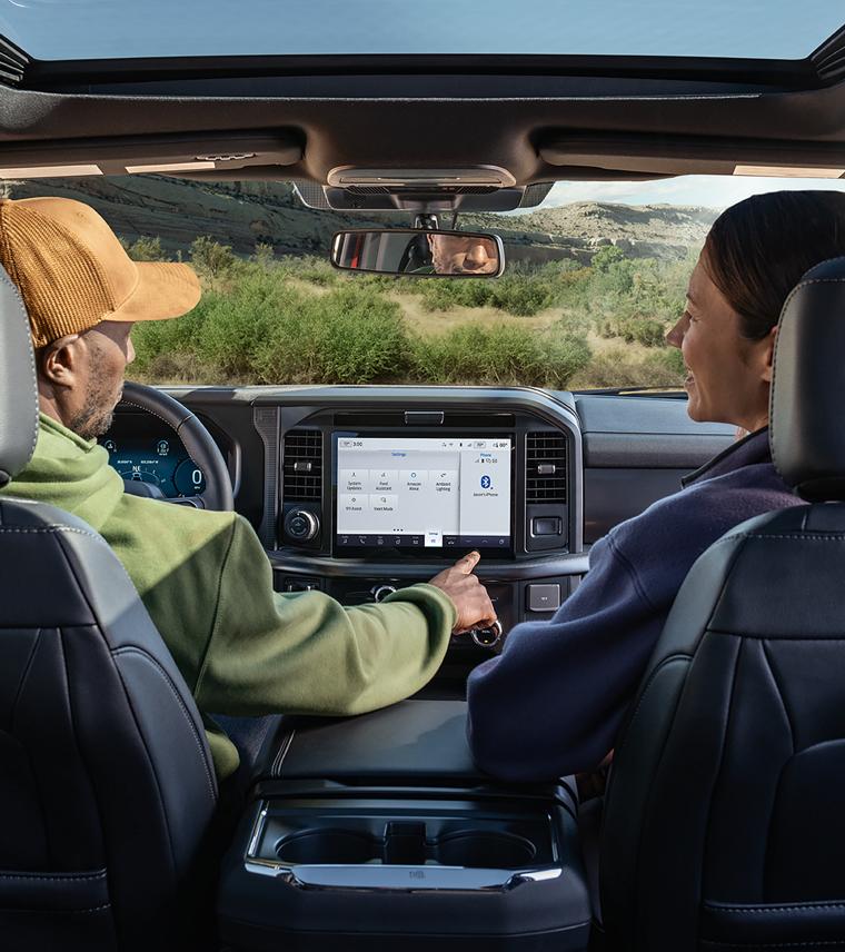 An interior shot of the front two seats of a 2026 Ford F-150® truck with a man and a woman talking