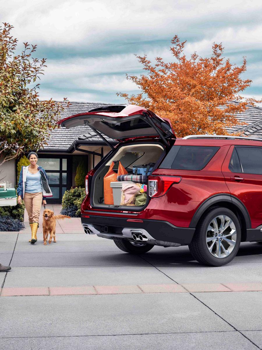 A couple with dog walk towards a Ford SUV