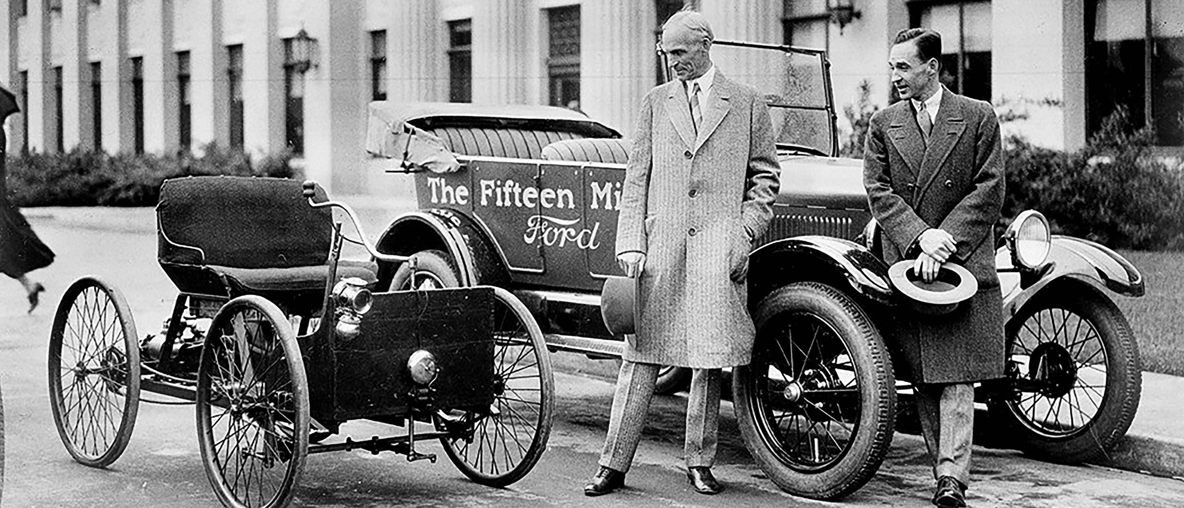 Henry and Edsel Ford take a moment to recognize company history in front of a lineup of the Ford Quadricycle and Model T