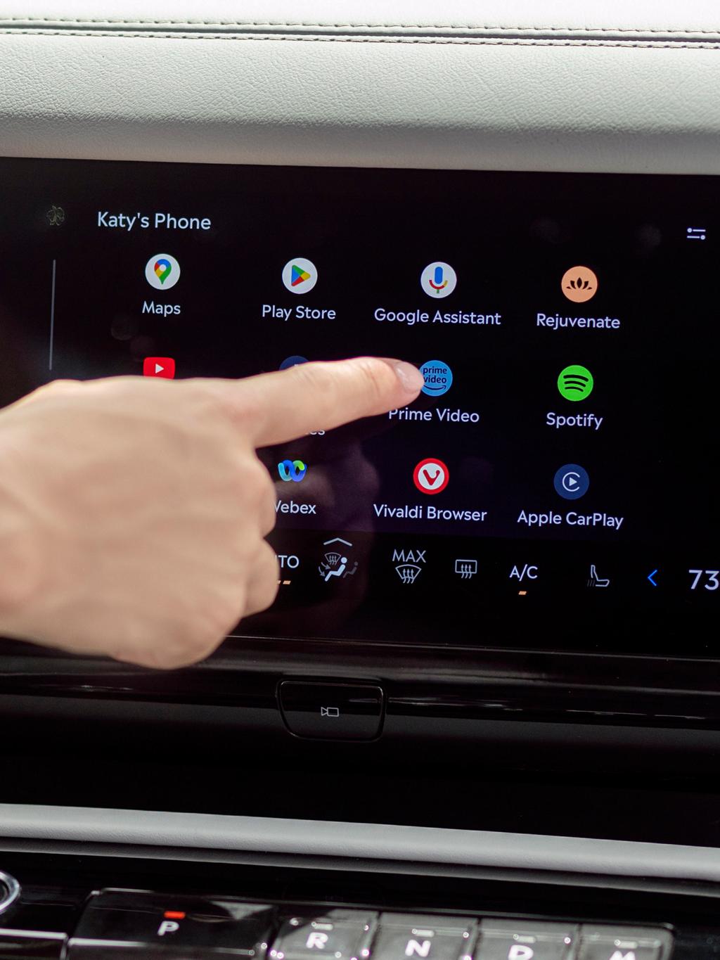 Un dedo presiona un botón en la pantalla táctil central dentro de una SUV Lincoln Navigator® 2026