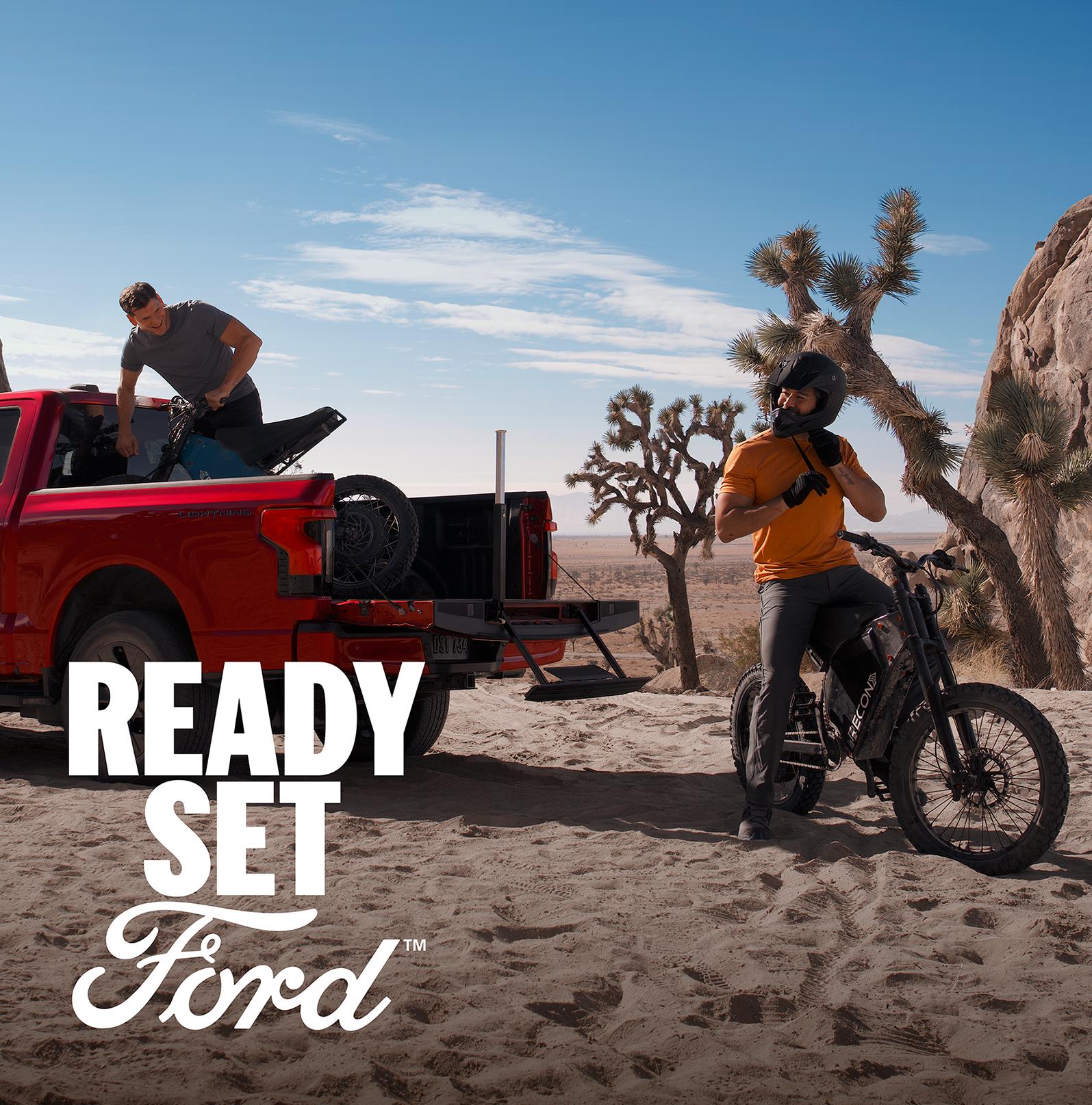 Two people unloading mountain bikes from the bed of a 2025 Ford F-150® Lightning®