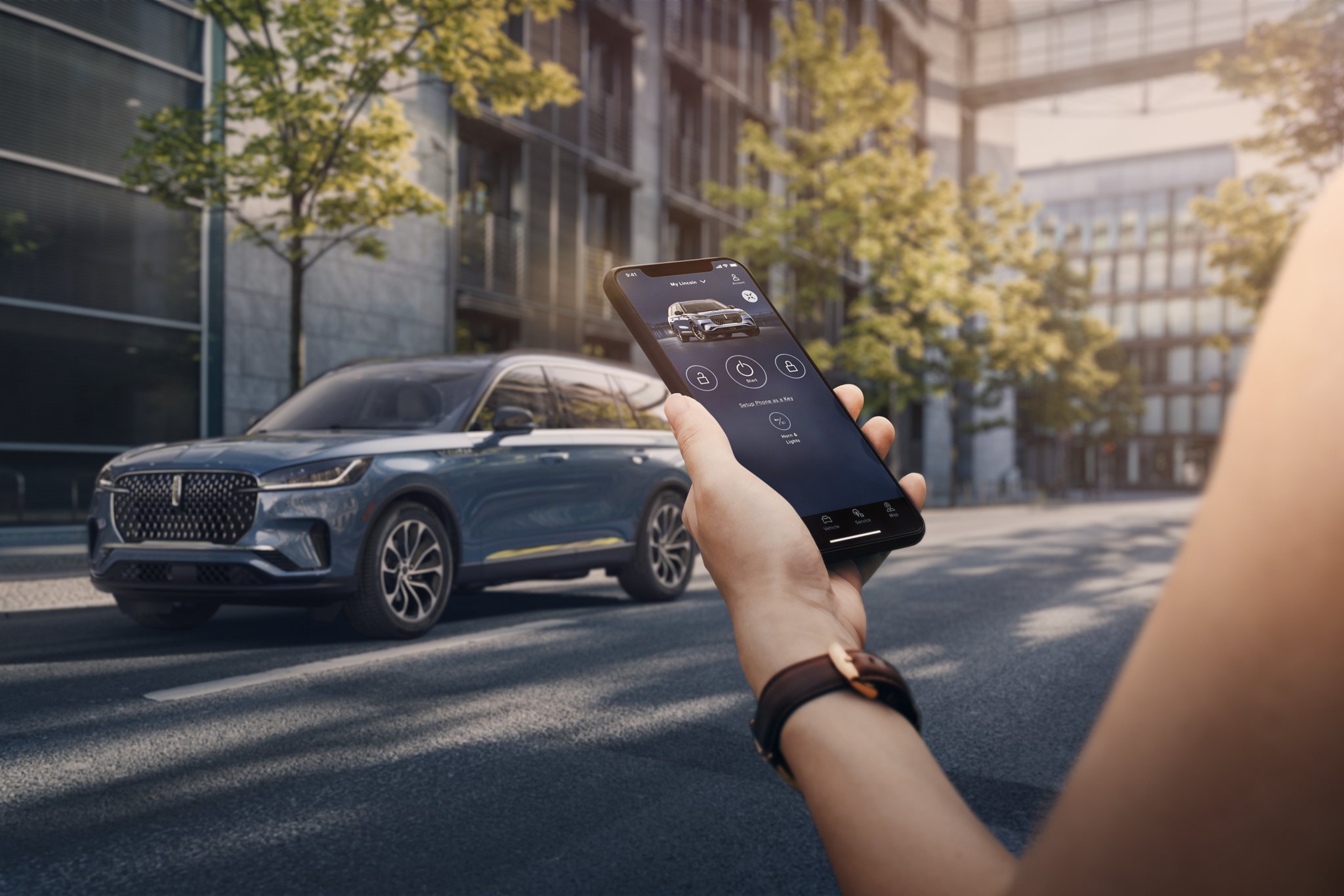 Une personne tient un smartphone à la main alors qu'elle s'approche d'un véhicule Lincoln.
