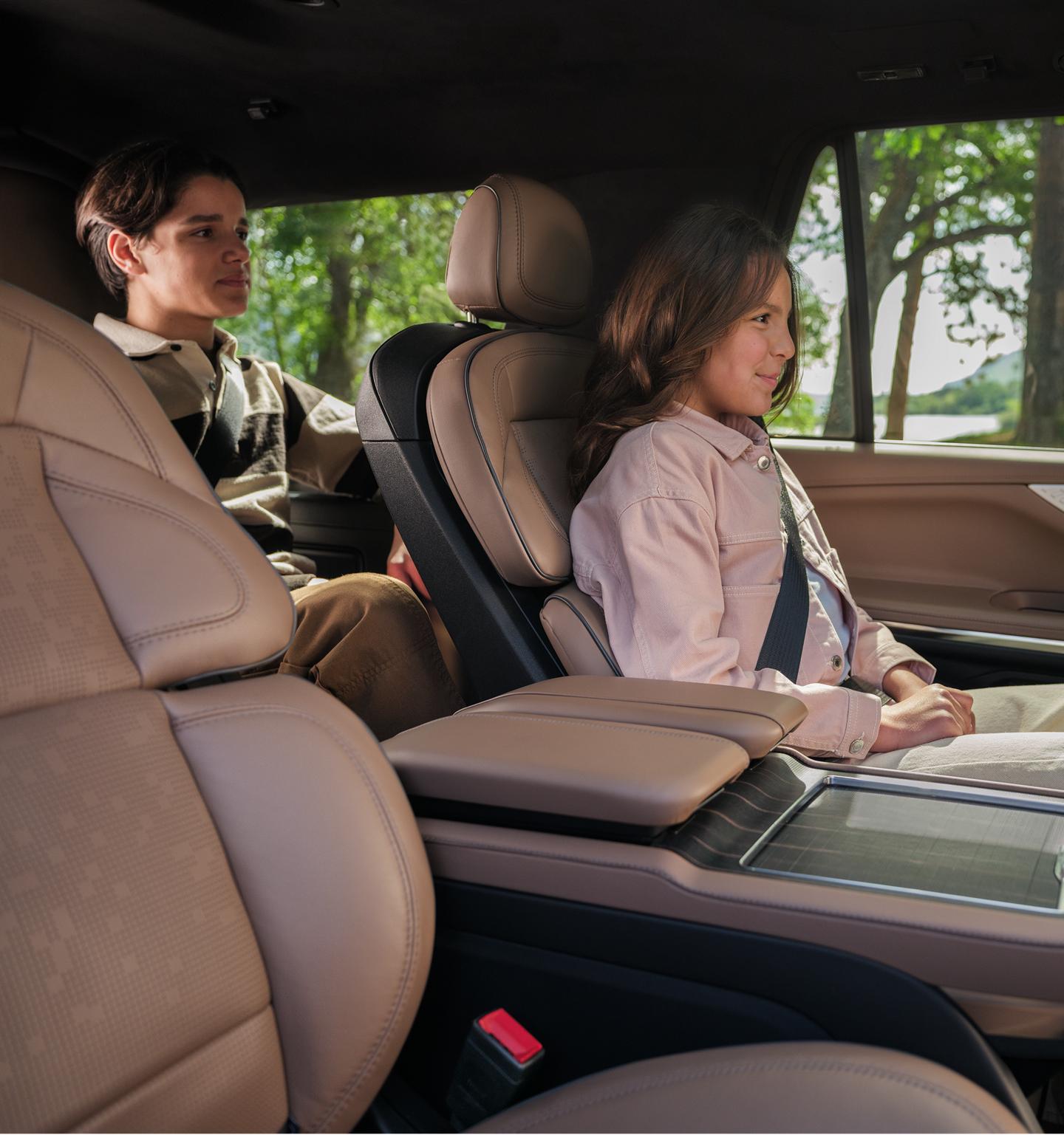 A child puts on his seatbelt while seated in the third row