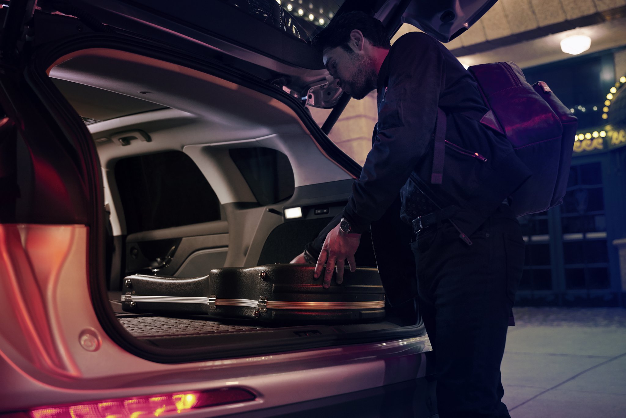 A man putting a guitar case in the trunk